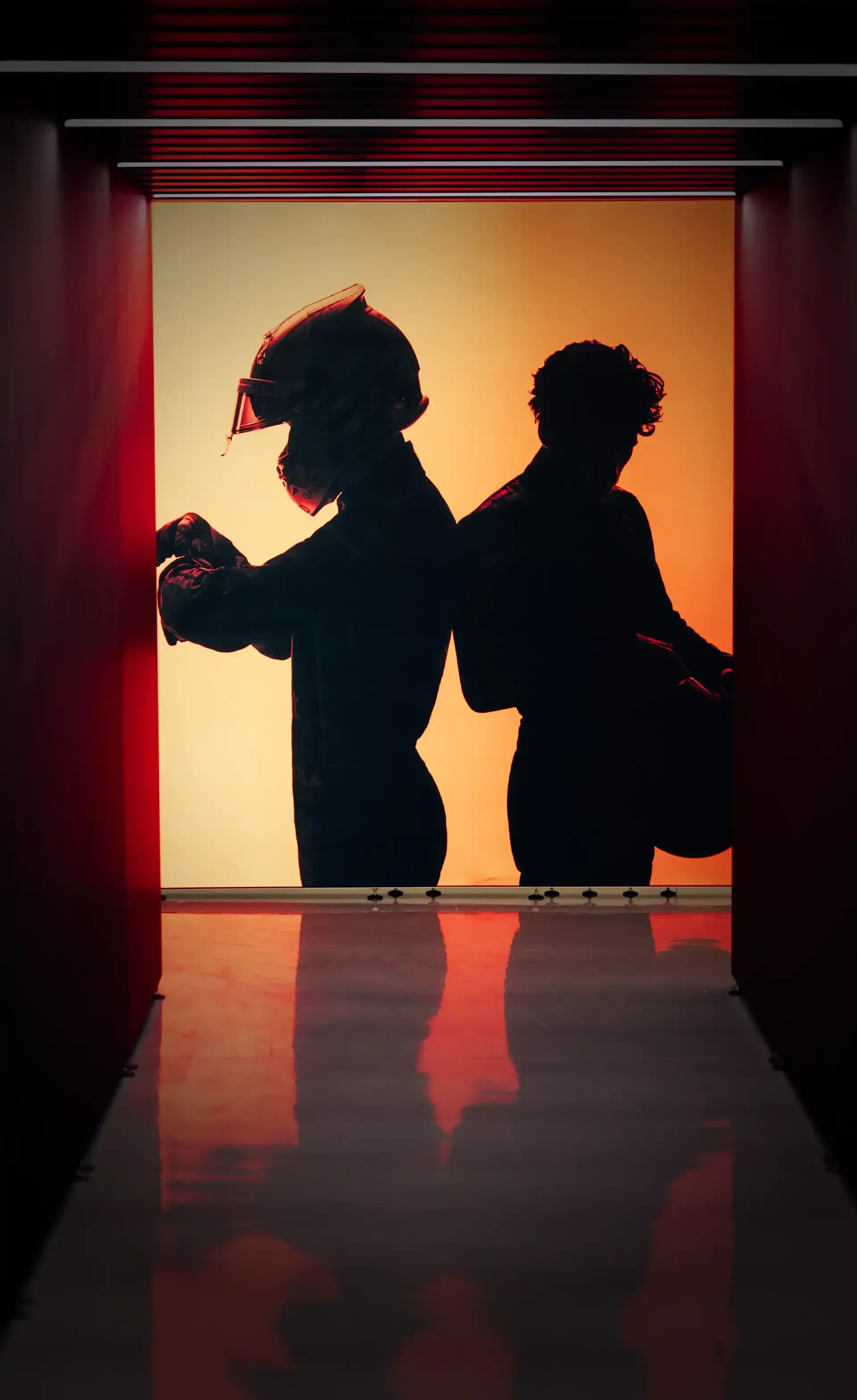 Dark silhouettes of Nico Hülkenberg on the left and Gabriel Bortoleto on the right, set against a lava-red background for the Audi Revolut F1® Team