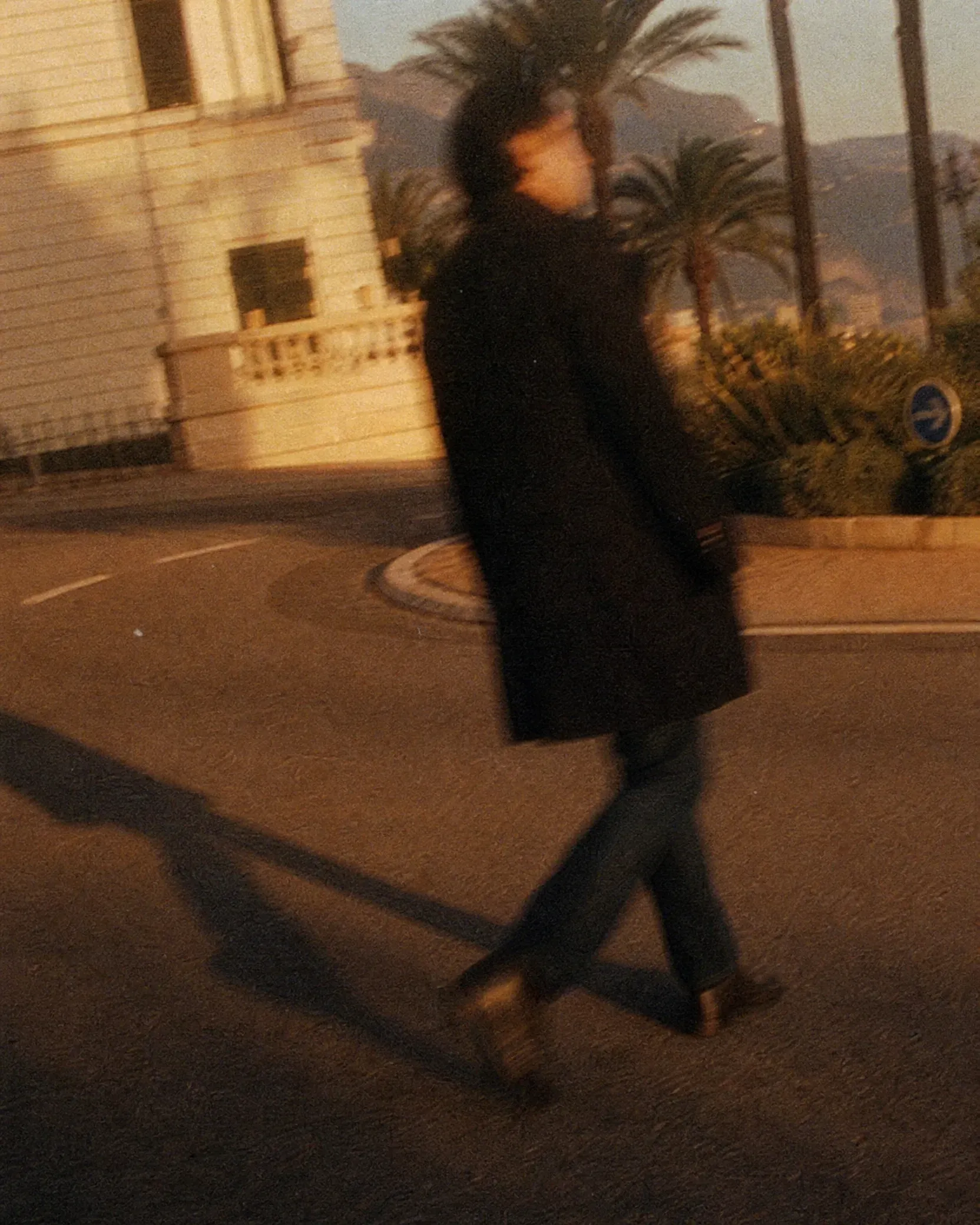 Person walking along a Monaco street at dusk, illuminated by warm golden-hour light.