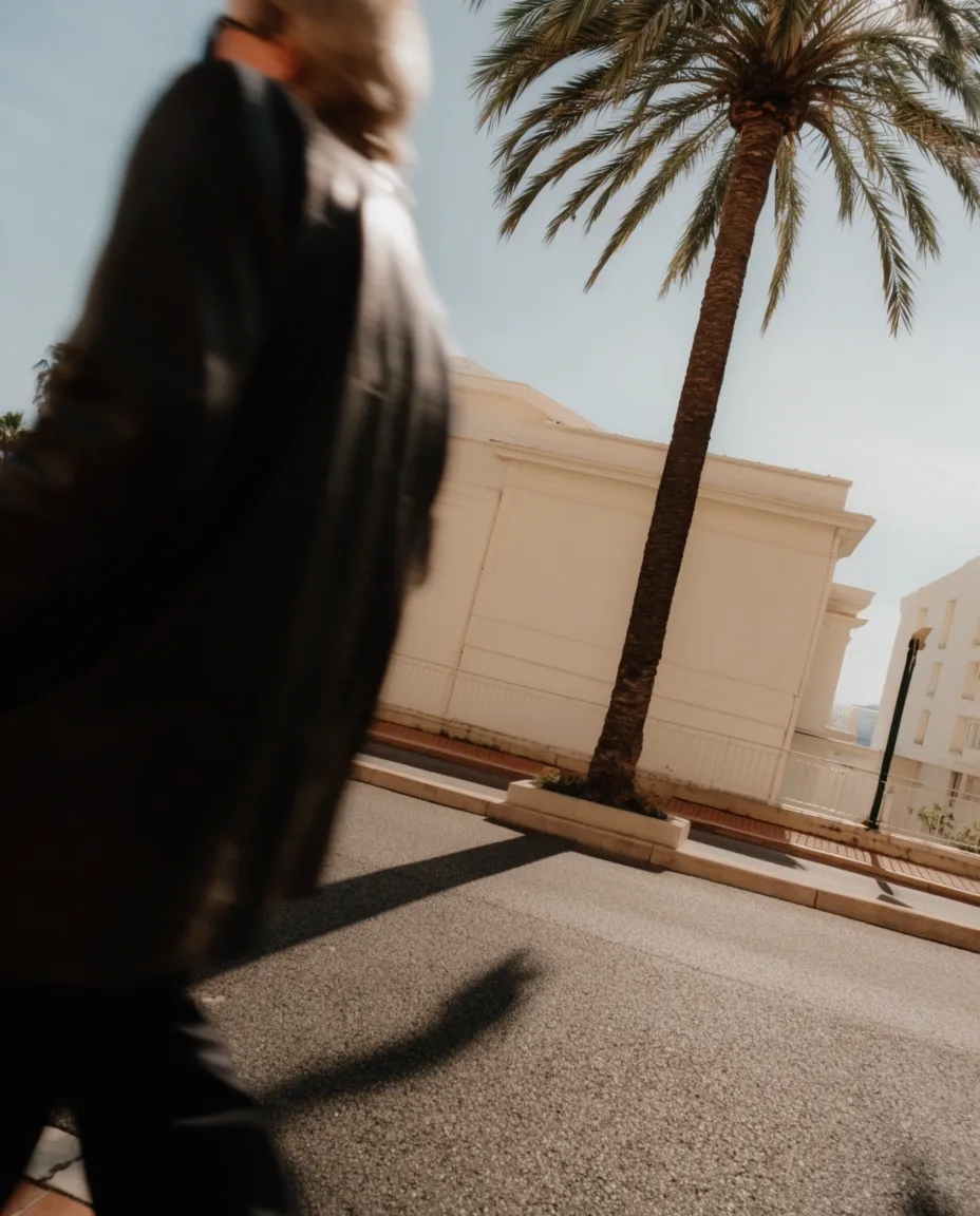 Low-angle view of palm trees and coastal architecture against a bright sky.