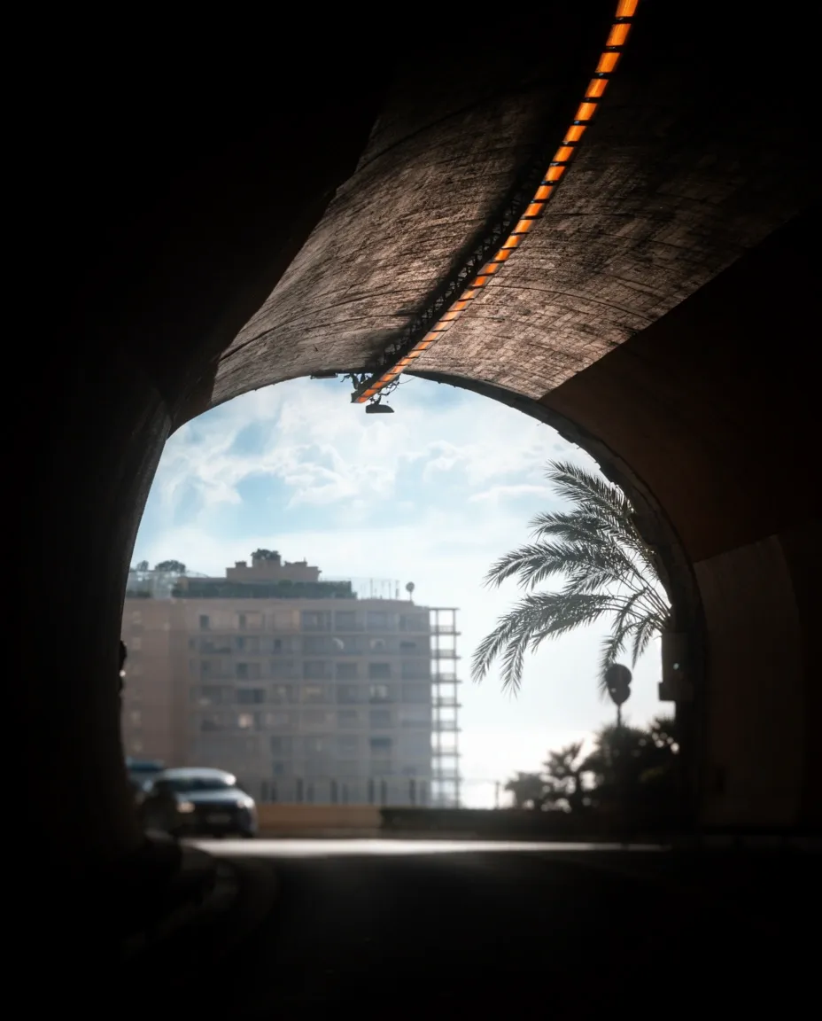 Dark tunnel interior leading toward a bright opening and the city beyond.
