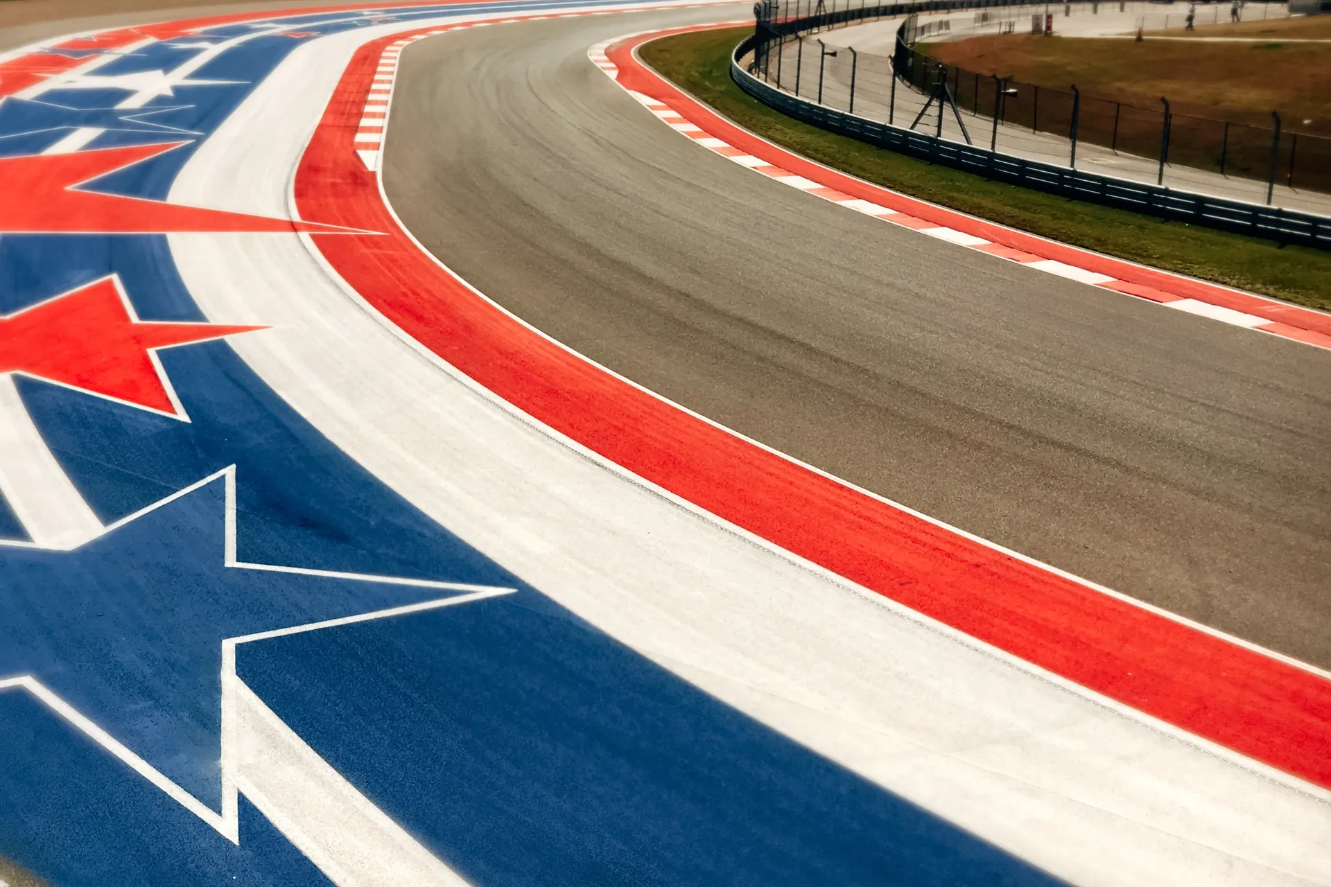Close-up of a curving race track with red, white and blue kerbs painted with stars.