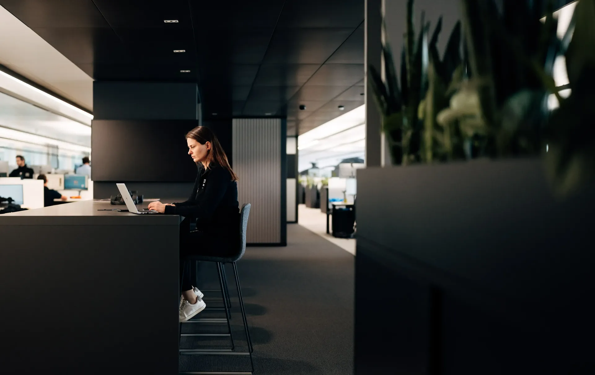Sandra Internal communications of Audi Revolut F1® Team sitting at a workstation with office space extending behind her.