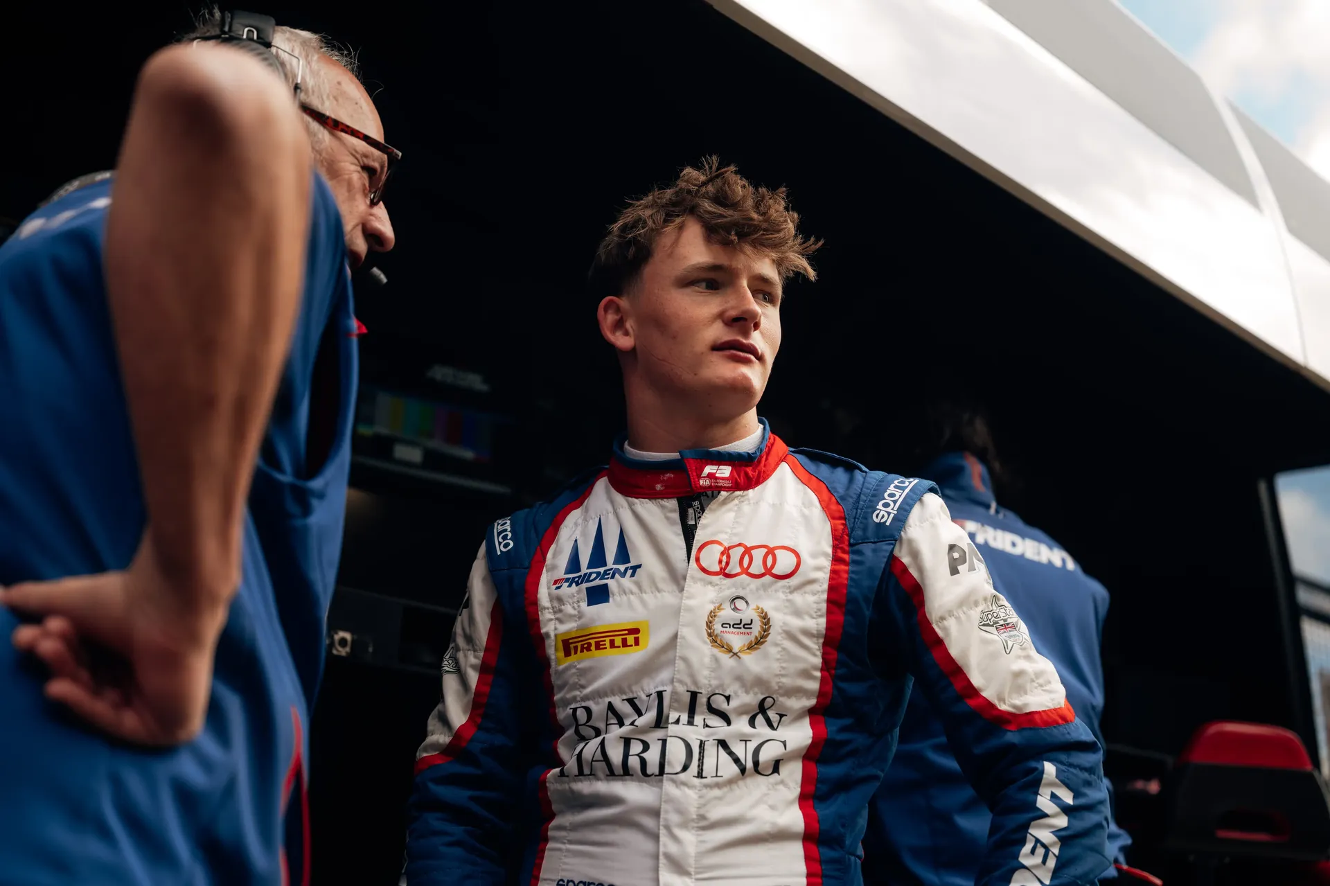 Formula 3 driver Freddie Slater standing in the paddock wearing his Audi race suit during a race weekend.