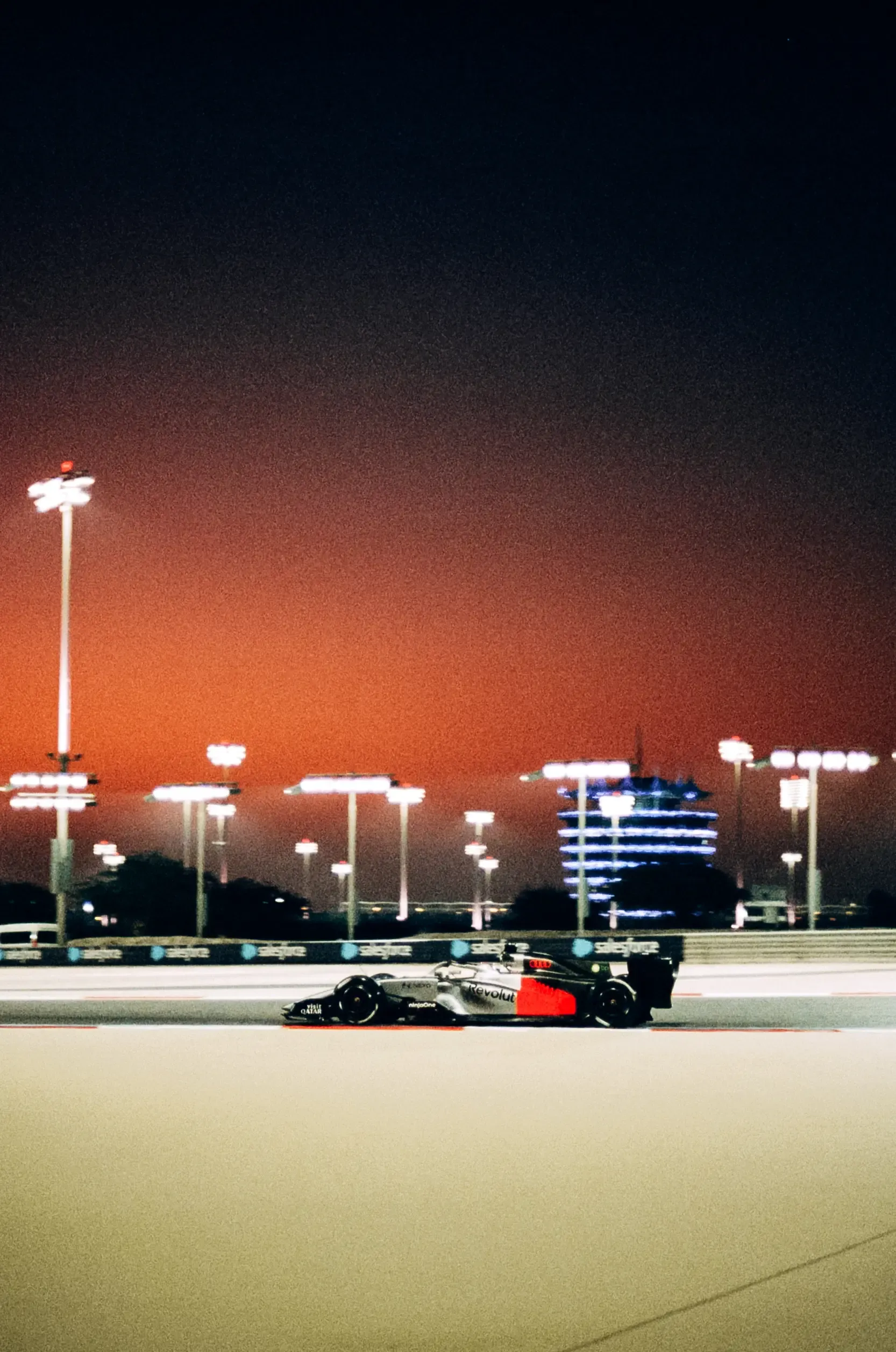 The Audi R26 drives around the illuminated circuit during an evening Formula 1® session.