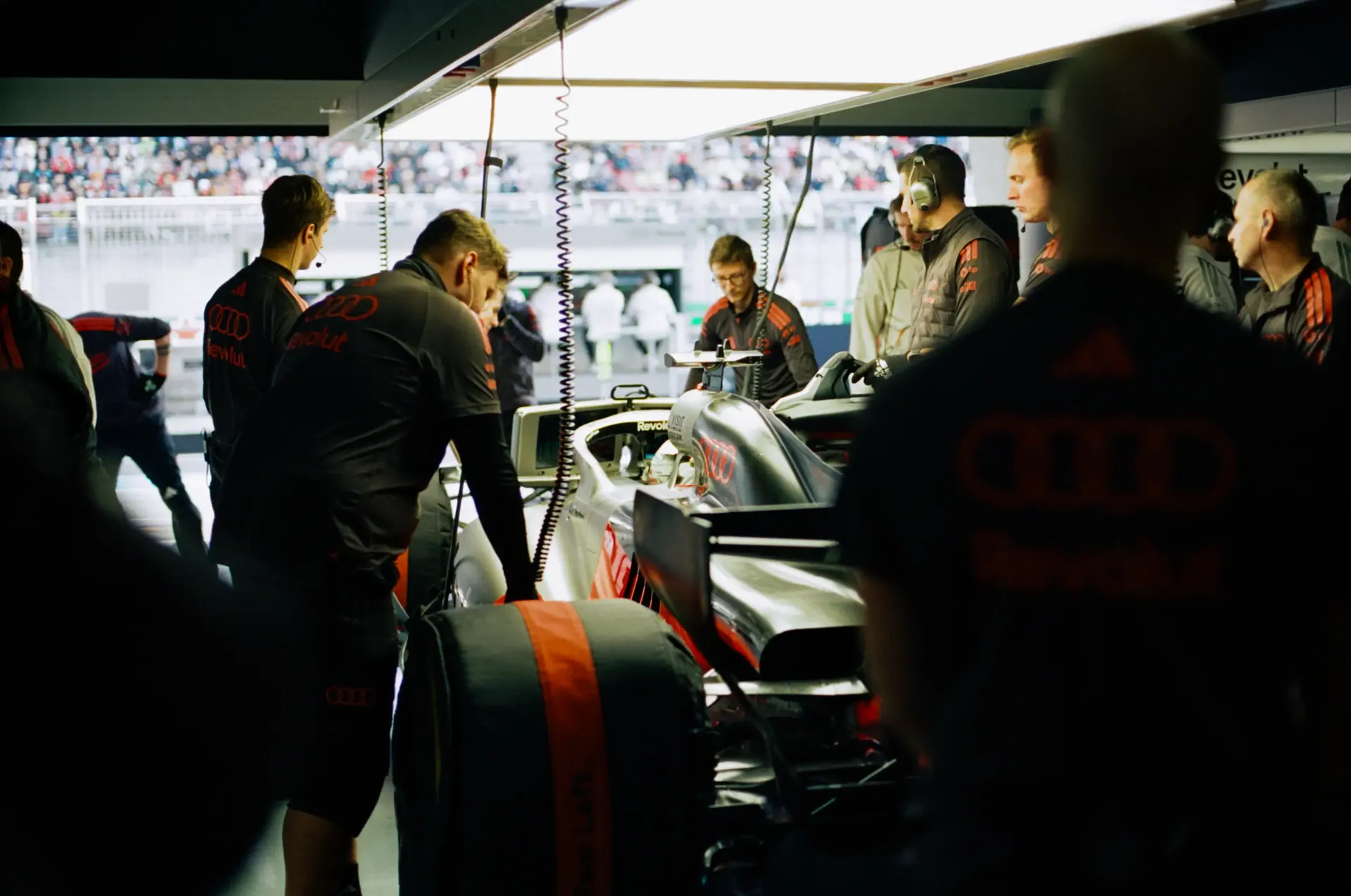 Audi Revolut F1® Team mechanics gather around the Audi R26 during preparations in the garage.