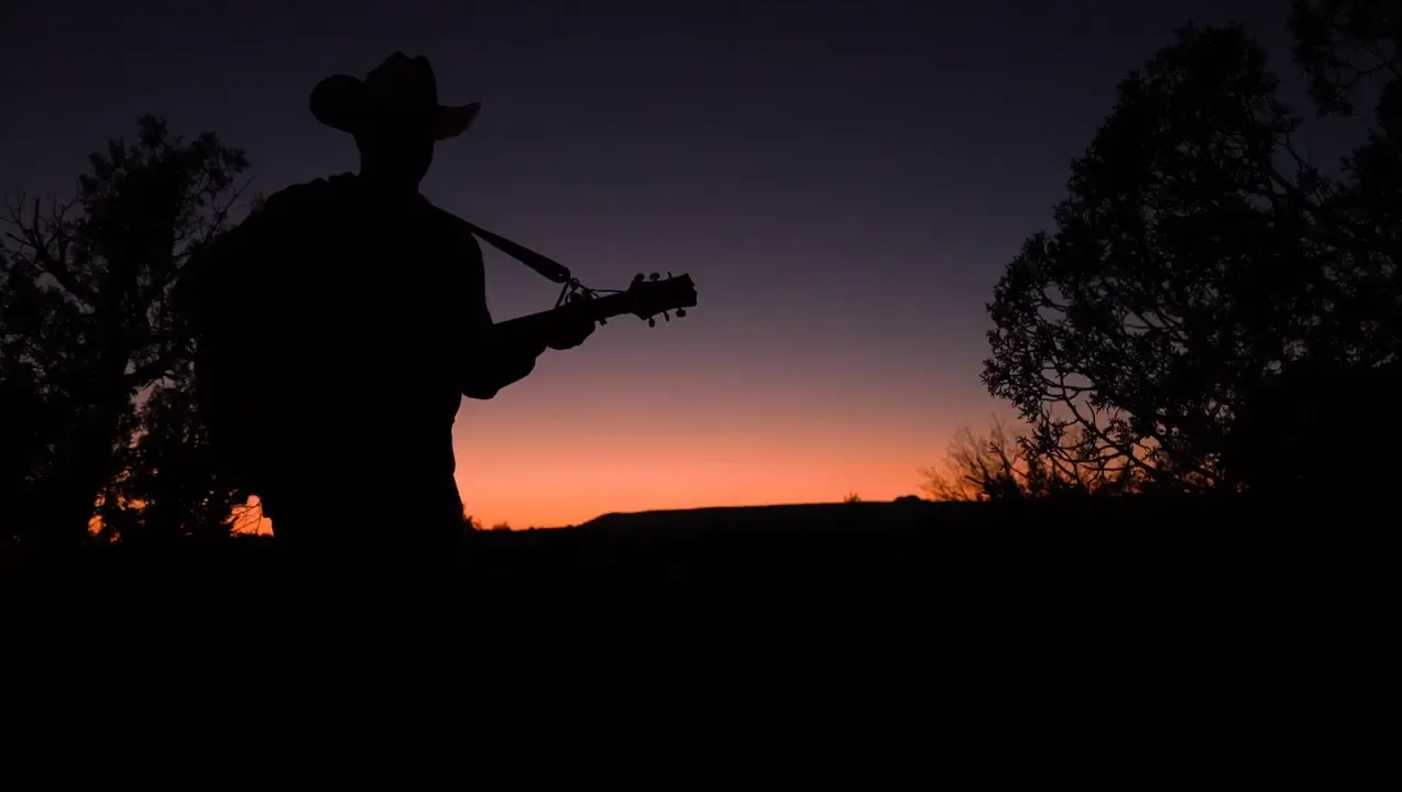 Cowboy silhouette with guitar at night