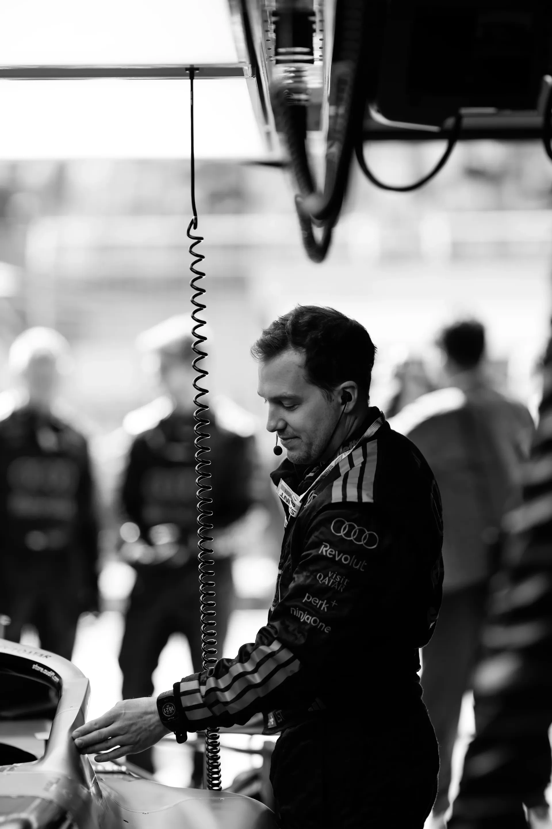 Crew member of the Audi Revolut F1® Team inside the garage preparing the car happy look