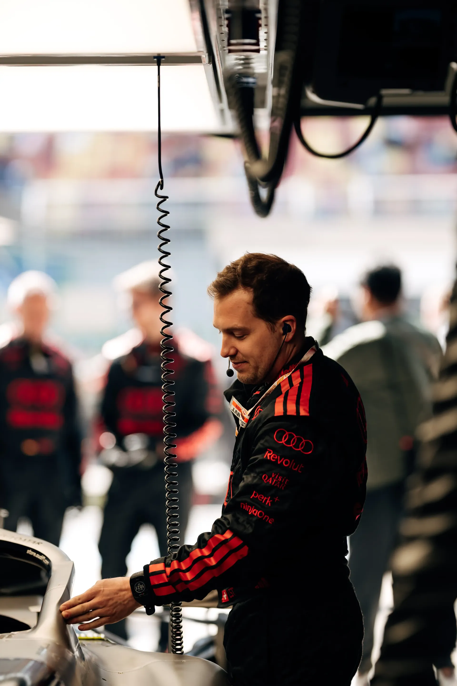 Crew member of the Audi Revolut F1® Team inside the garage preparing the car happy look