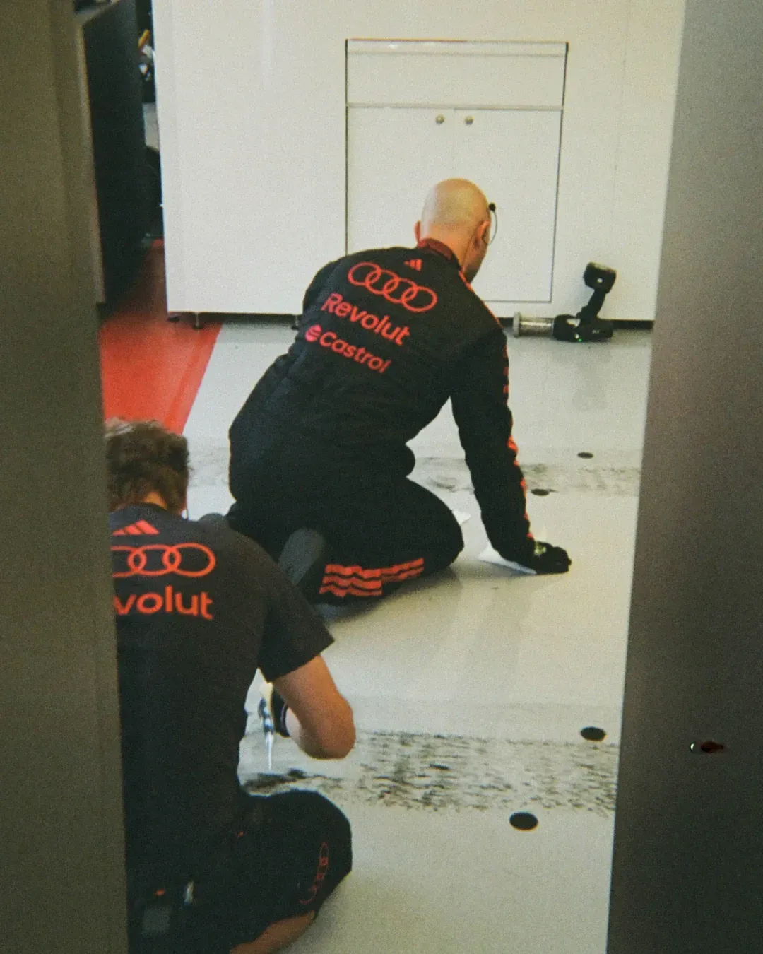 Audi Revolut F1® Team members crouch on the garage floor while cleaning the workspace.