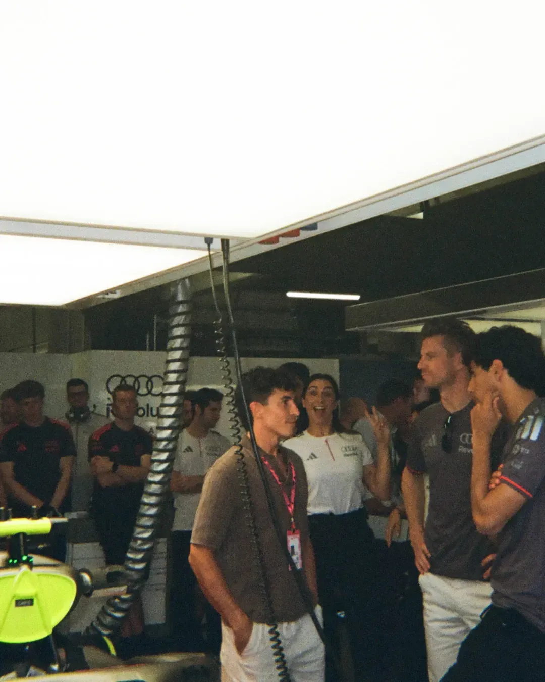 Audi Revolut F1® Team members and guests chat inside the garage beside the race car.