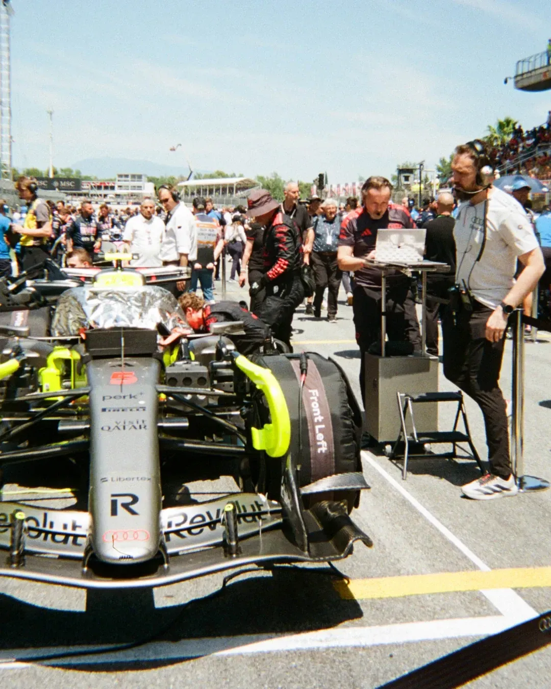 The Audi Revolut F1® race car sits on the grid as team members prepare it before the session.
