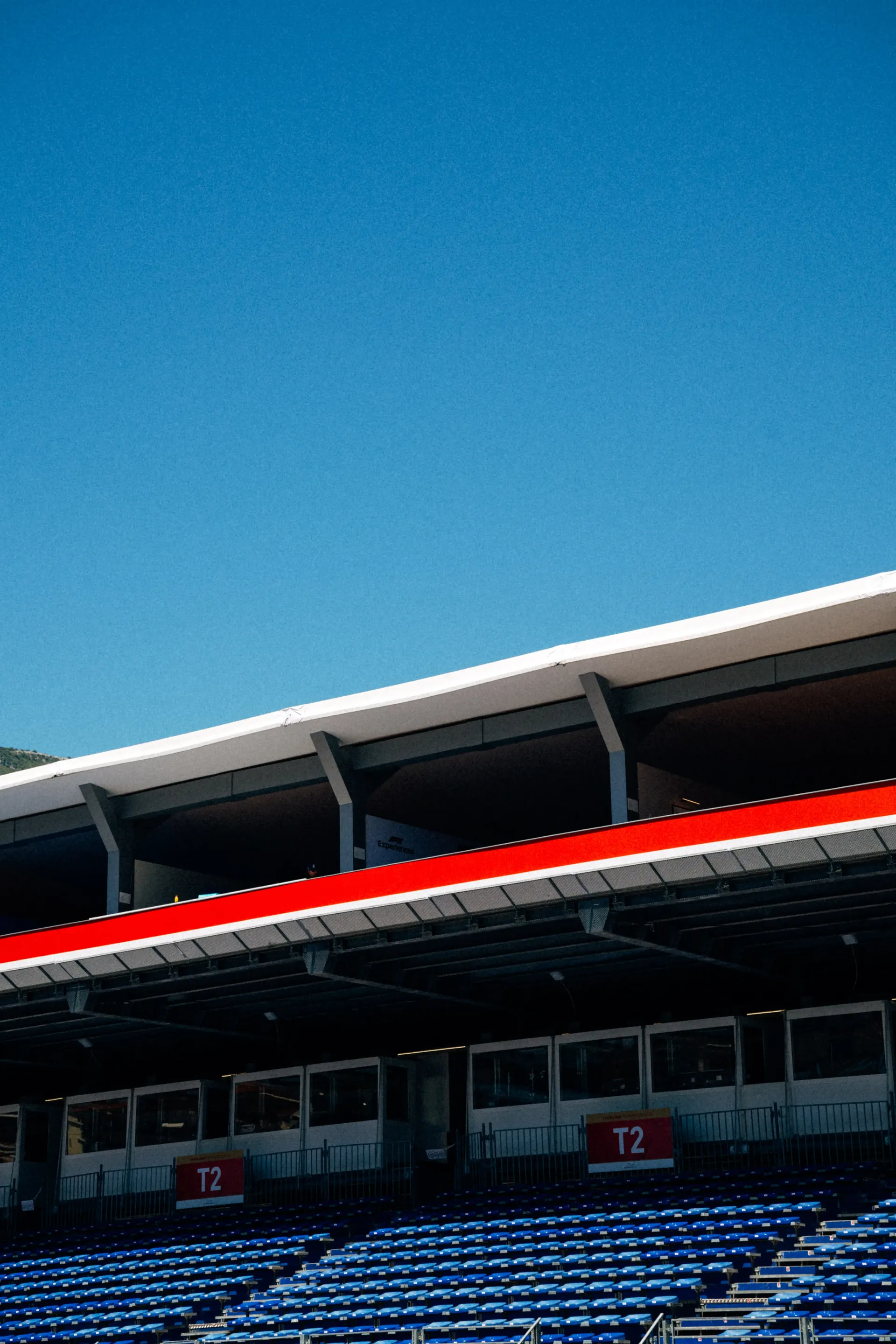 Empty Formula 1 grandstand under a clear blue sky with red roof detail
