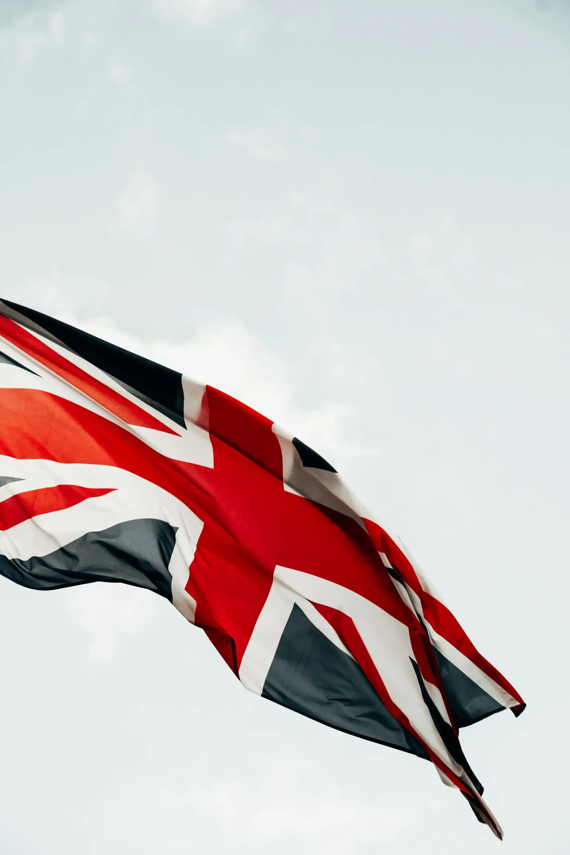 British Union Jack flag waving against a bright blue sky.