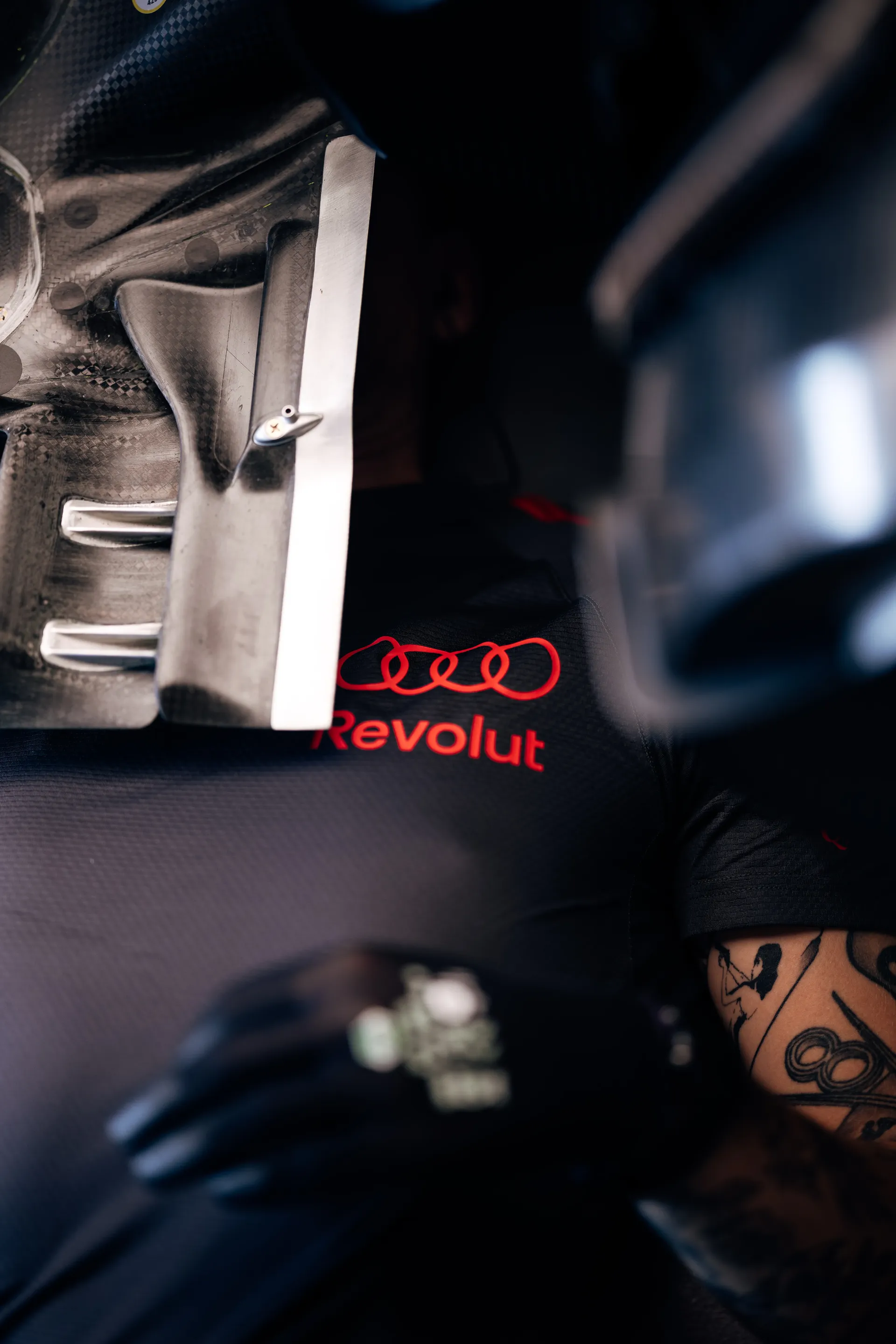 Close-up of an Audi Revolut F1® Team mechanic wearing black and red teamwear.
