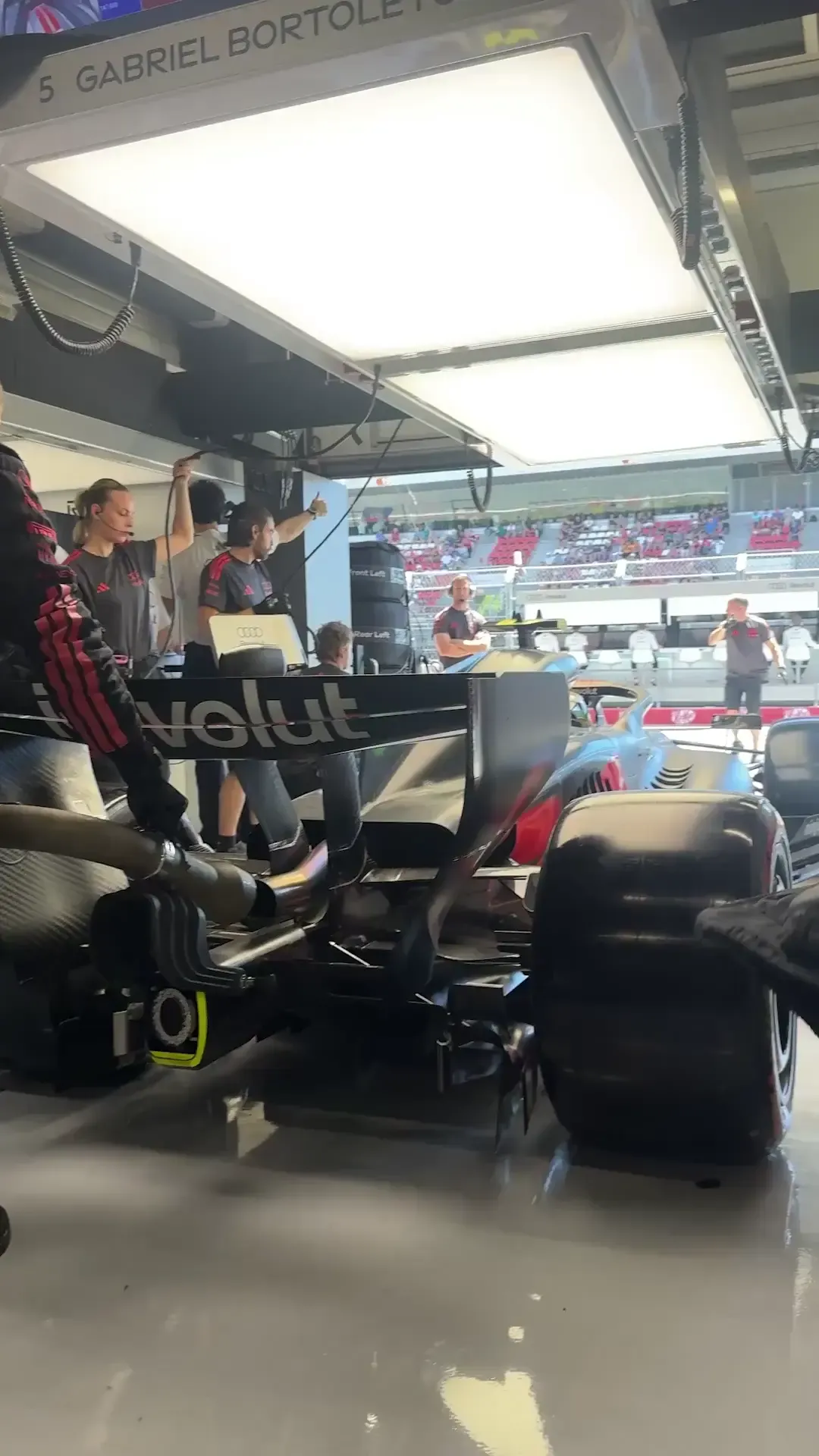 Audi Revolut F1® Team car exiting the Barcelona garage during race weekend preparations, capturing the transition from pit lane to track