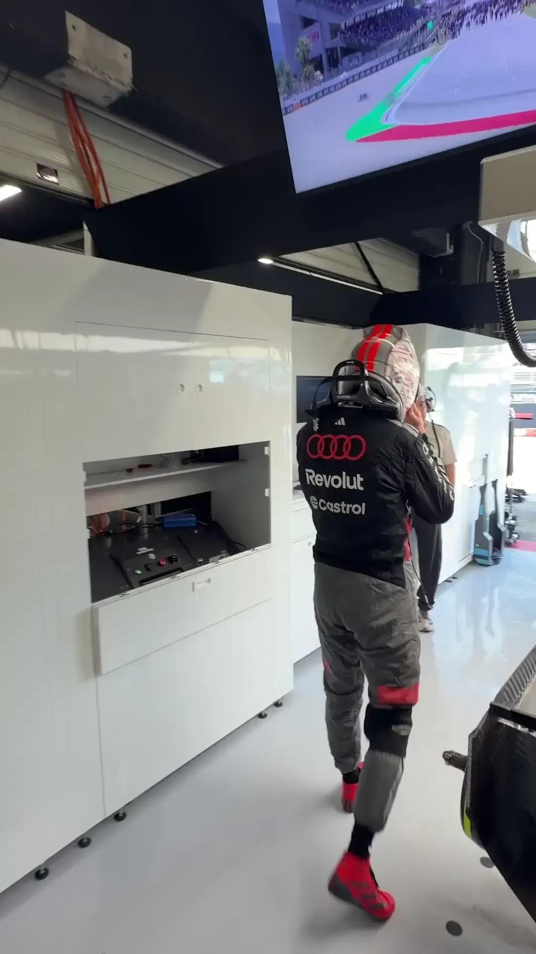 Nico Hulkenberg climbing into his Audi Revolut F1® Team car inside the garage, preparing for an on-track session