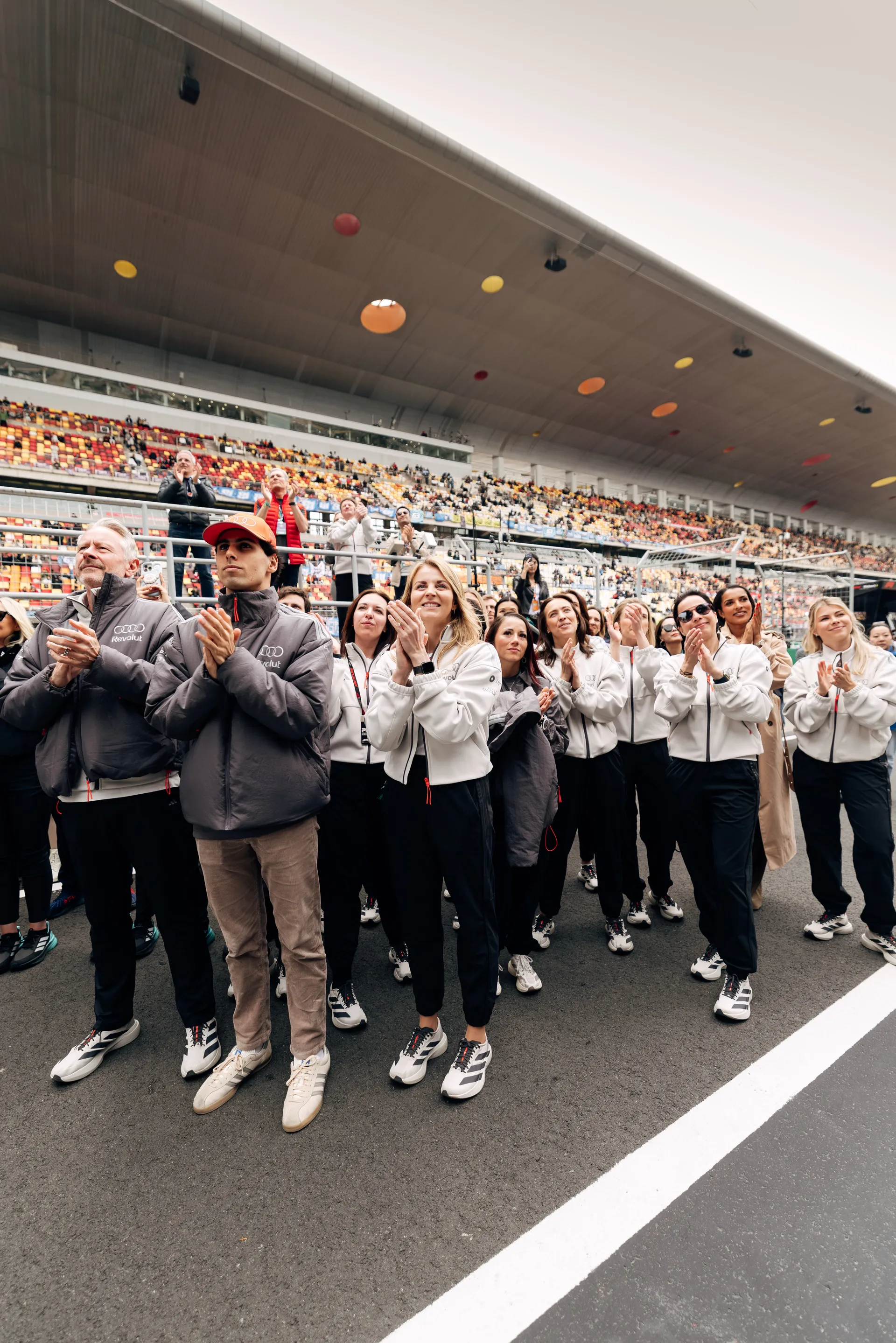 Audi Revolut F1® Team members, including Jonathan Wheatley and Gabriel Bortoleto, applaud trackside during Emma Felbermayr’s podium moment in Shanghai.