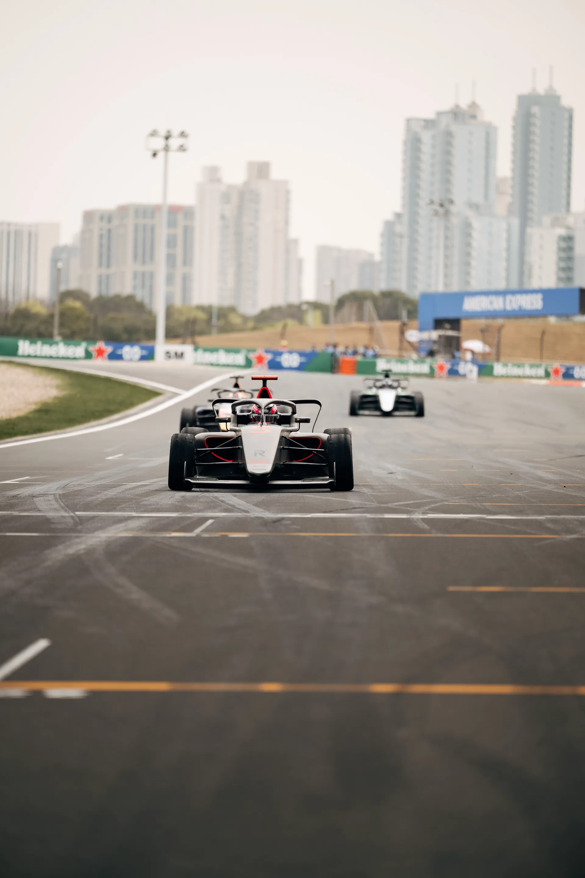 Emma Felbermayr leads an F1 Academy car on track in Shanghai with the city skyline visible in the background during Race 2.