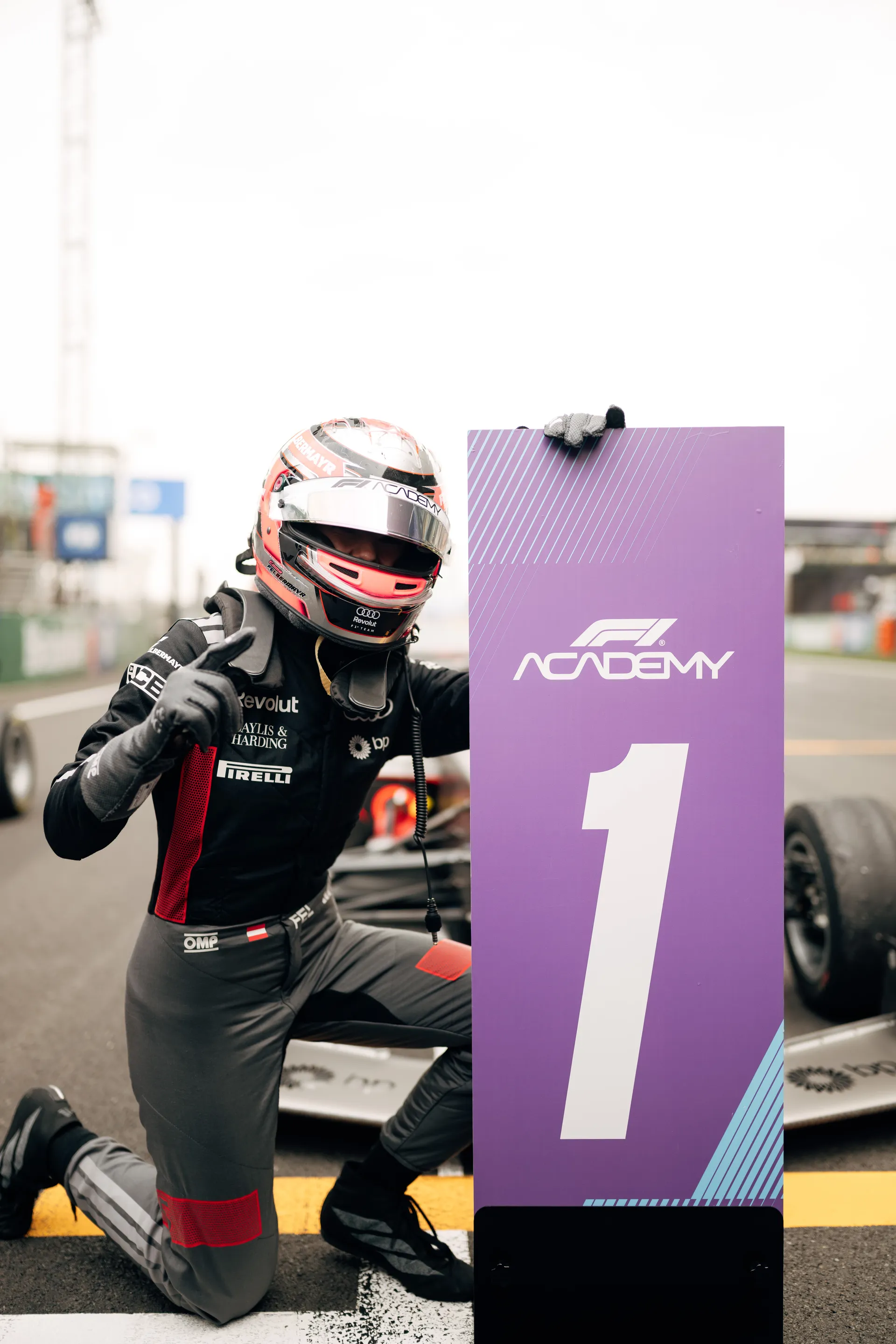 Emma Felbermayr kneels beside a purple F1 Academy number one board after Race 2 in Shanghai.