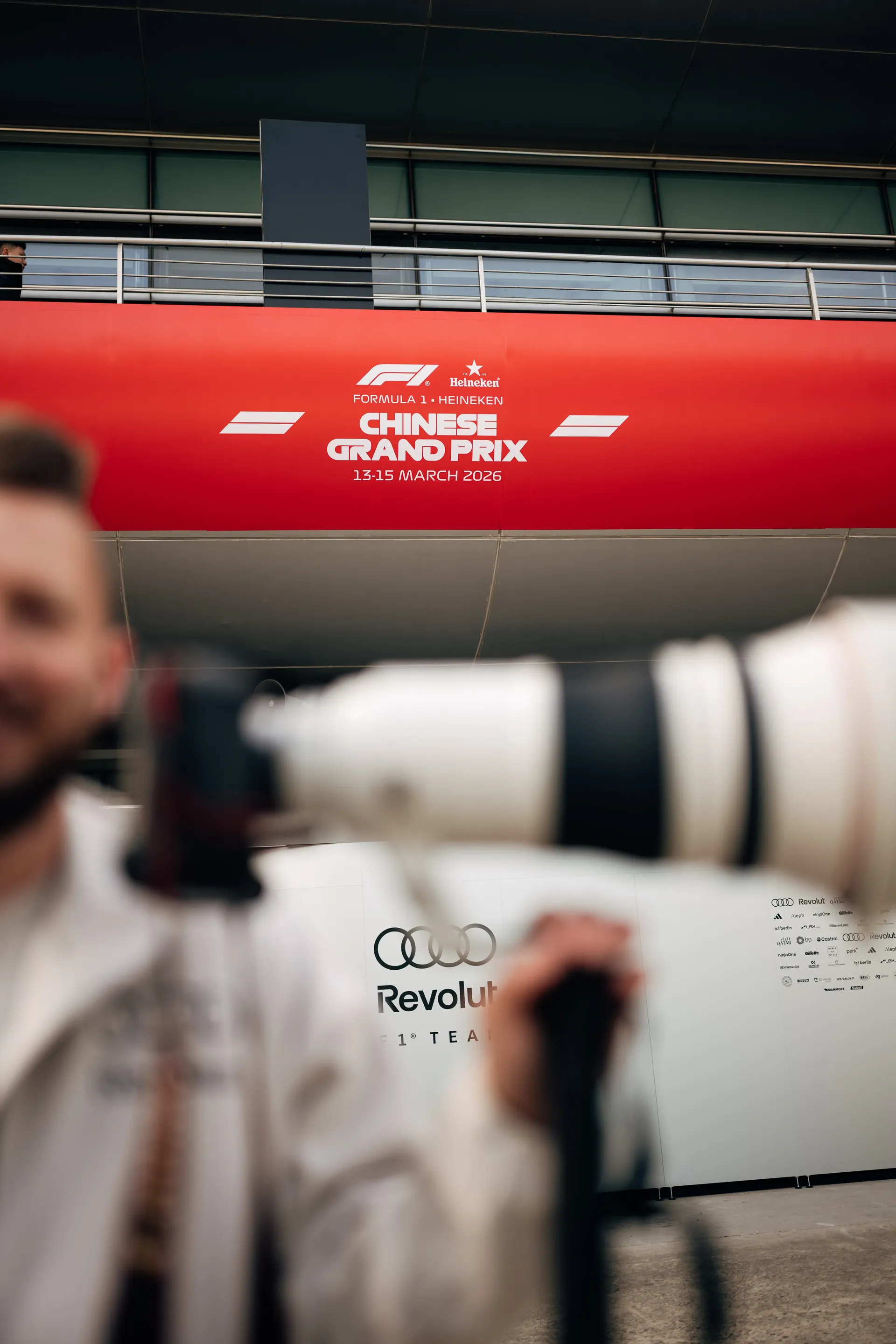 Chinese Grand Prix signage above the Audi Revolut F1® Team garage, with camera equipment and a blurred foreground figure in view.