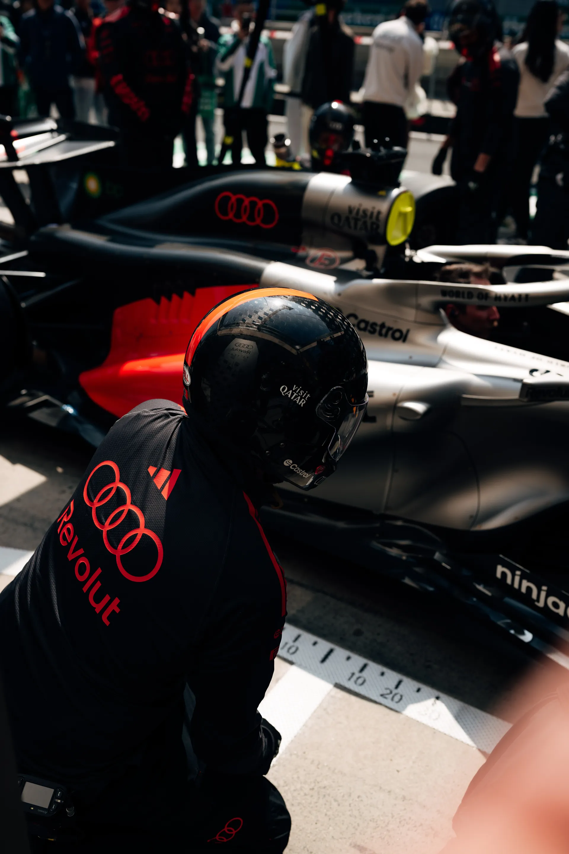 Audi Revolut F1® Team pit crew kneels beside the race car in the Shanghai pit lane during pit stop practice.