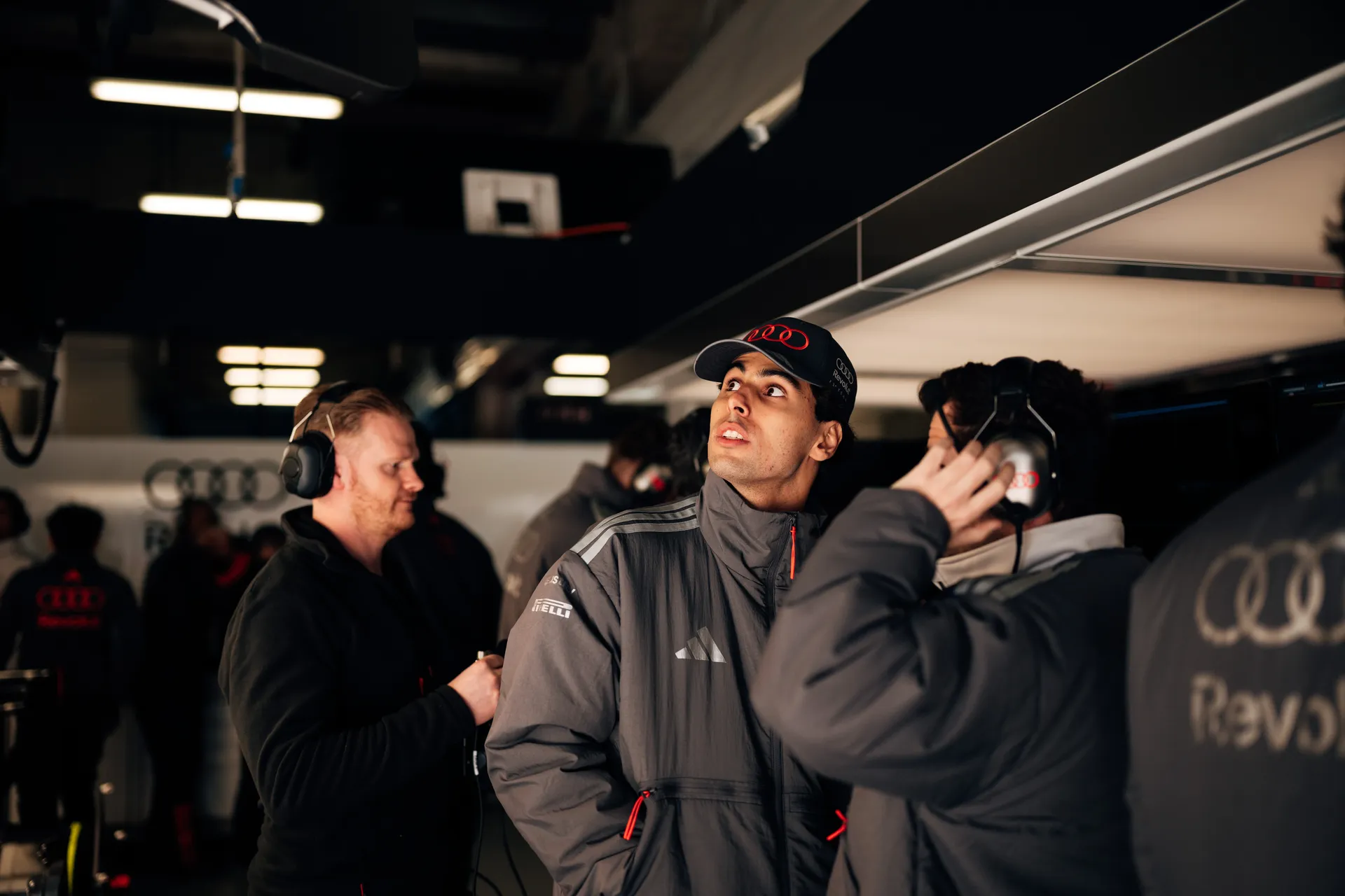 Side profile of Gabriel Bortoleto inside the Shanghai garage, wearing Audi Revolut F1® Team gear during race weekend preparations.