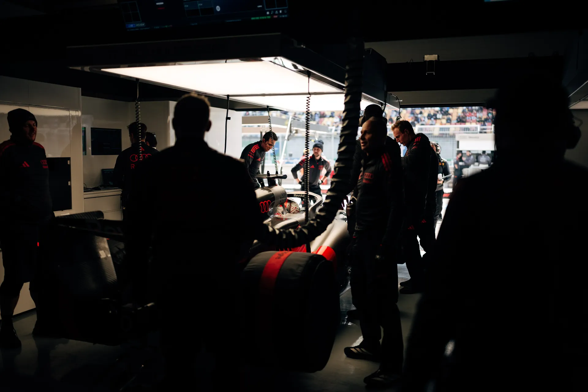 Audi Revolut F1® Team crew gather around the race car inside the Shanghai garage during practice preparations.
