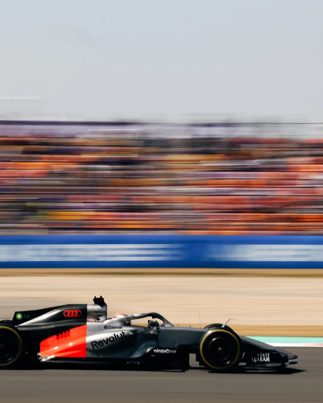Audi Revolut F1® Team car on track in Shanghai, captured in motion with blurred grandstands in the background.
