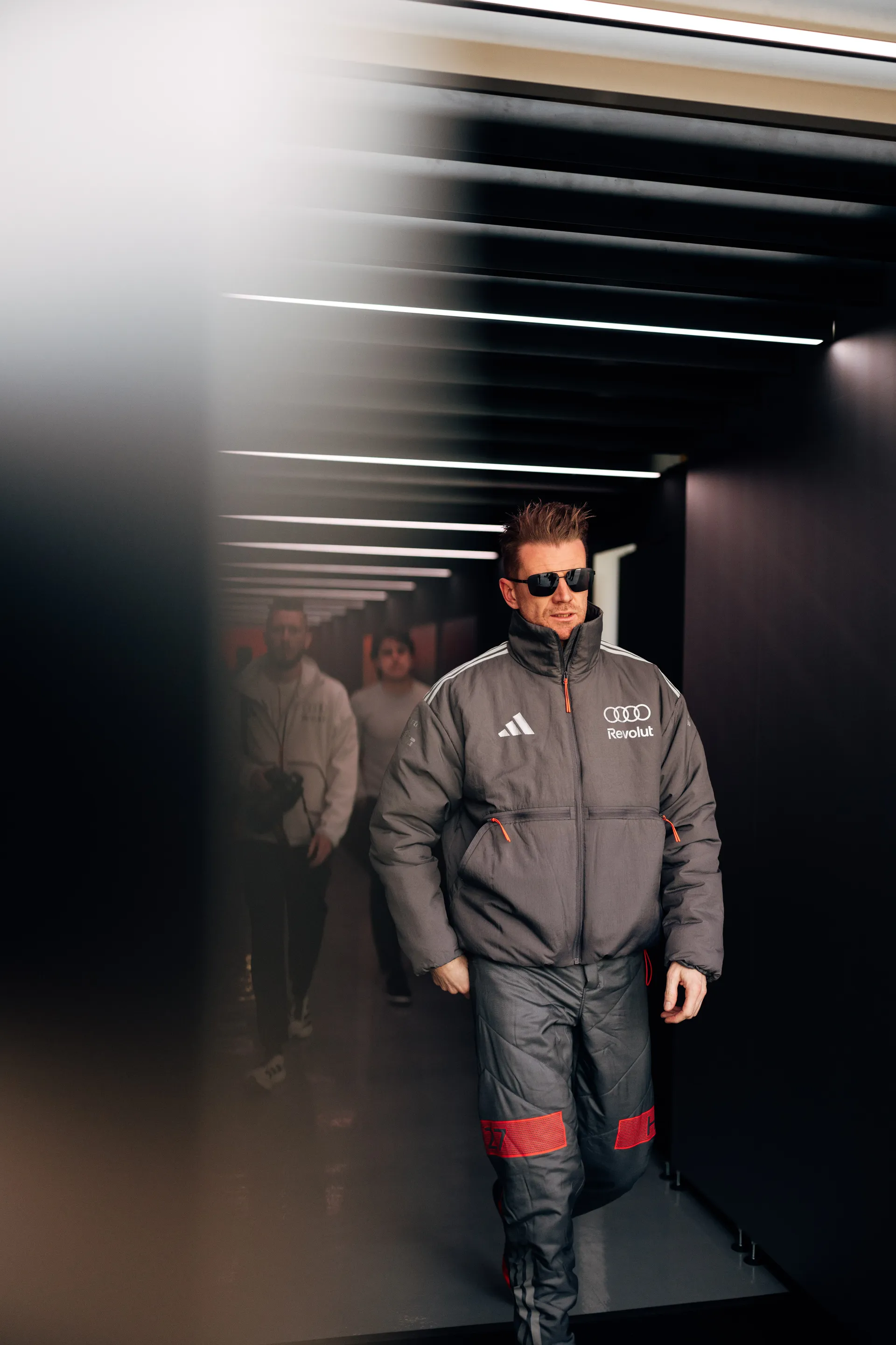 Nico Hulkenberg walks through the Audi Revolut F1® Team garage tunnel in Shanghai wearing sunglasses.