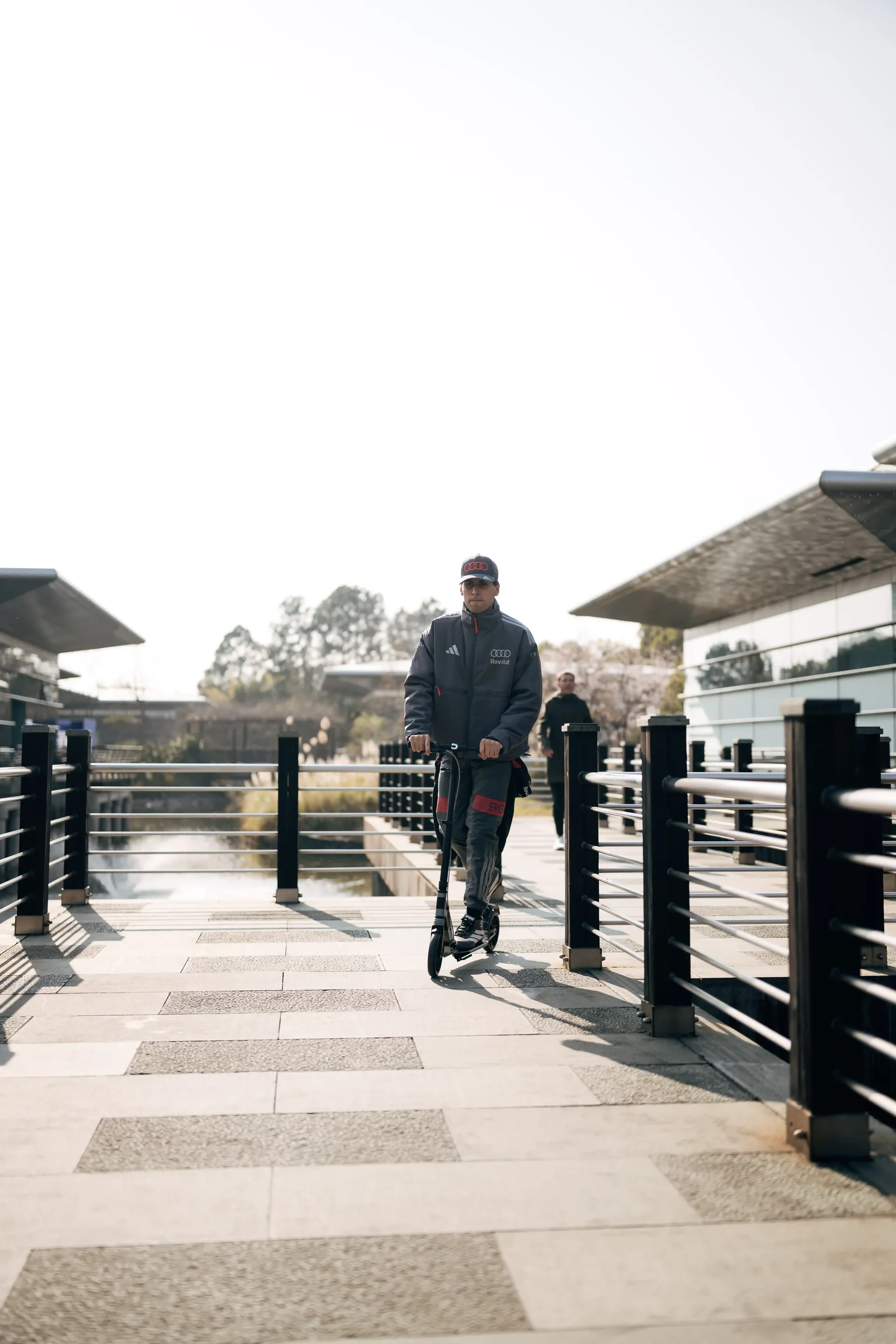 Audi Revolut F1® Team member Gabriel Bortoleto walking along a pit lane bridge walkway at a racing circuit.