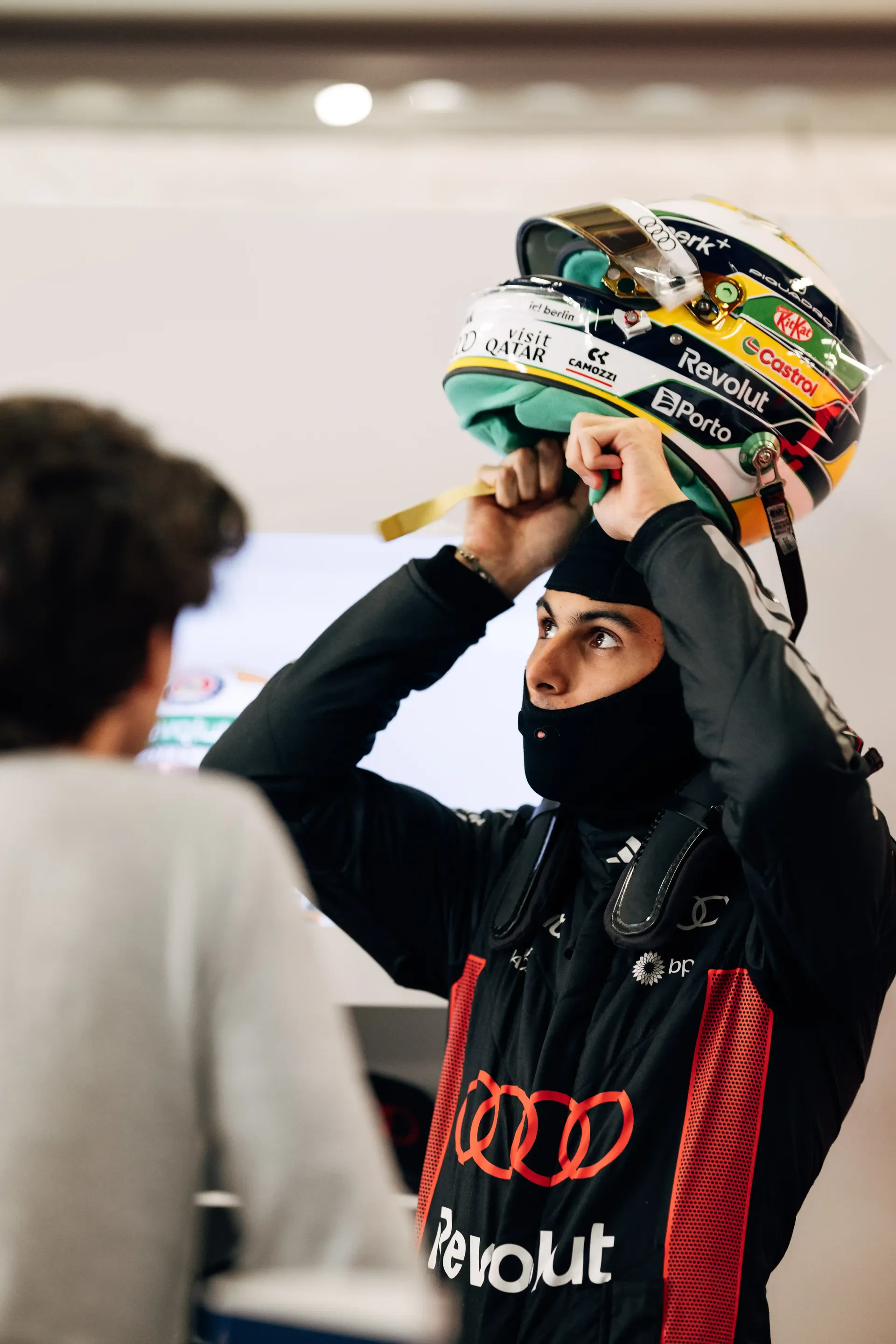 Audi Revolut F1® Team driver Gabriel Bortoleto putting on a racing helmet inside the team garage before a session.