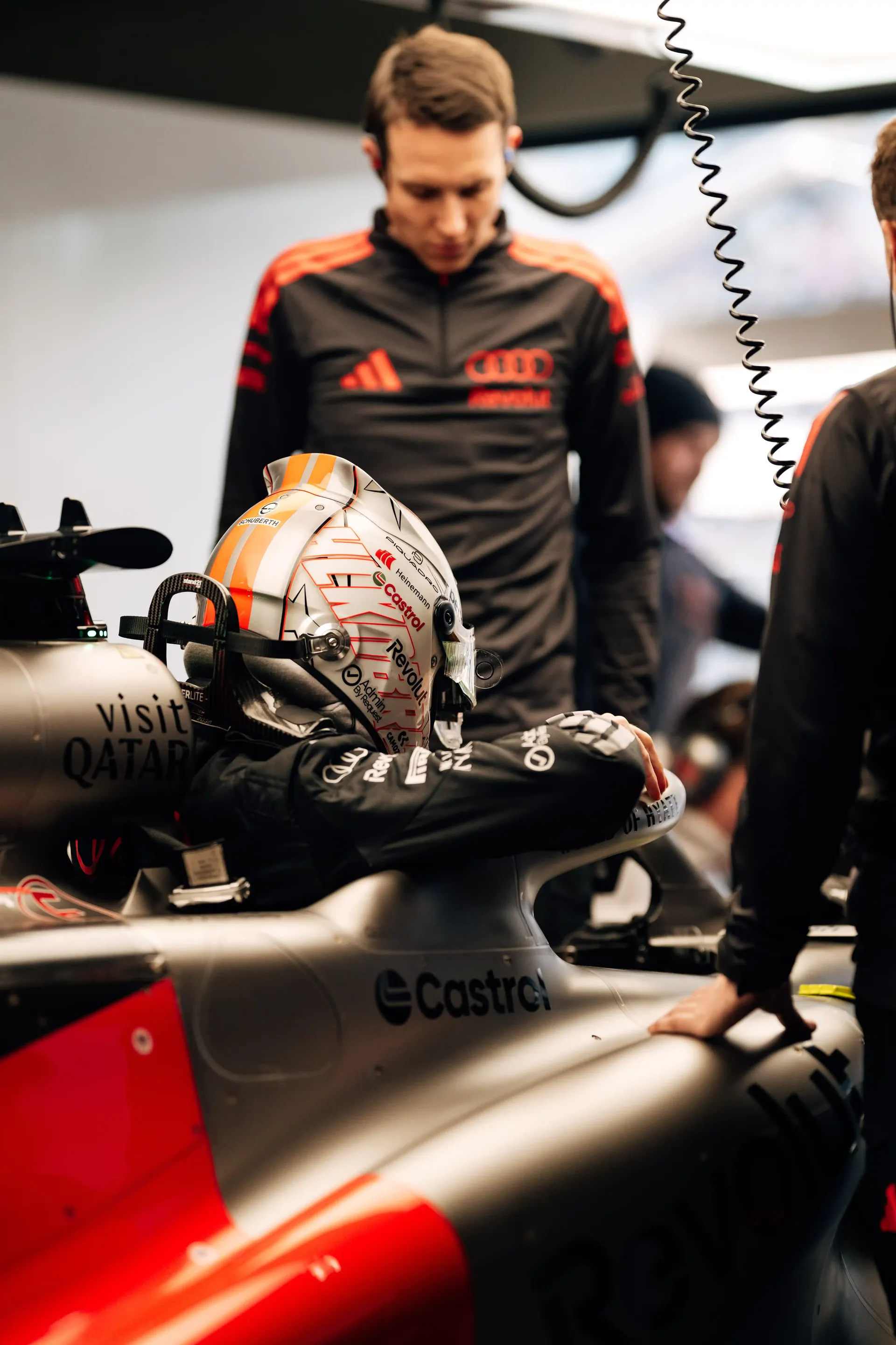 Audi Revolut F1® Team mechanic preparing the cockpit area of a Formula 1 race car inside the team garage.