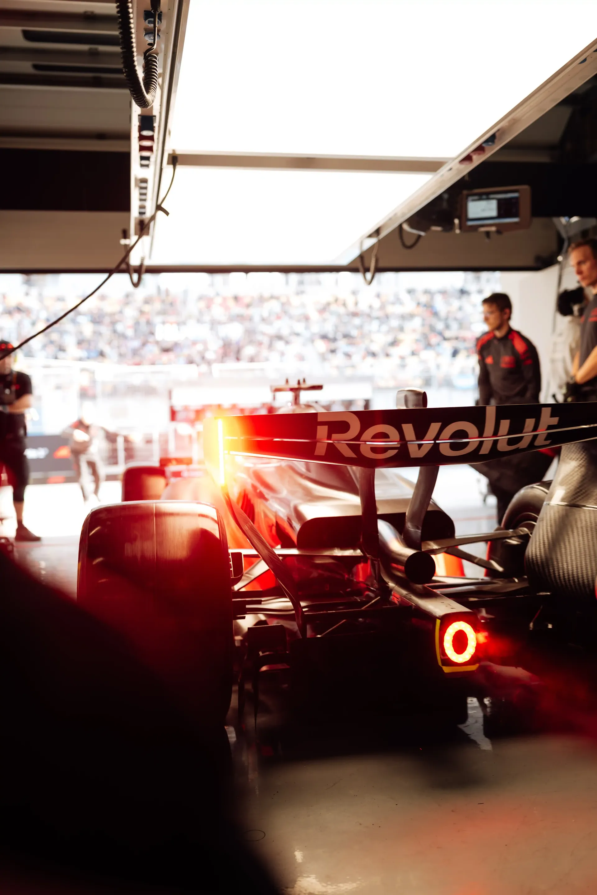 Rear view of an Audi Revolut F1® Team Formula 1 car with glowing rain light inside the pit garage.