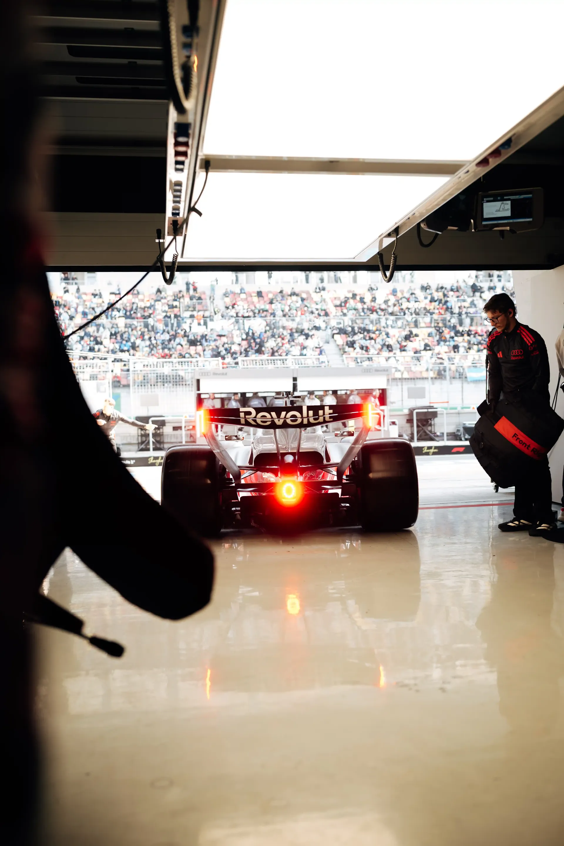 Audi Revolut F1® Team Formula 1 car driving out of the garage toward the pit lane during race preparations.
