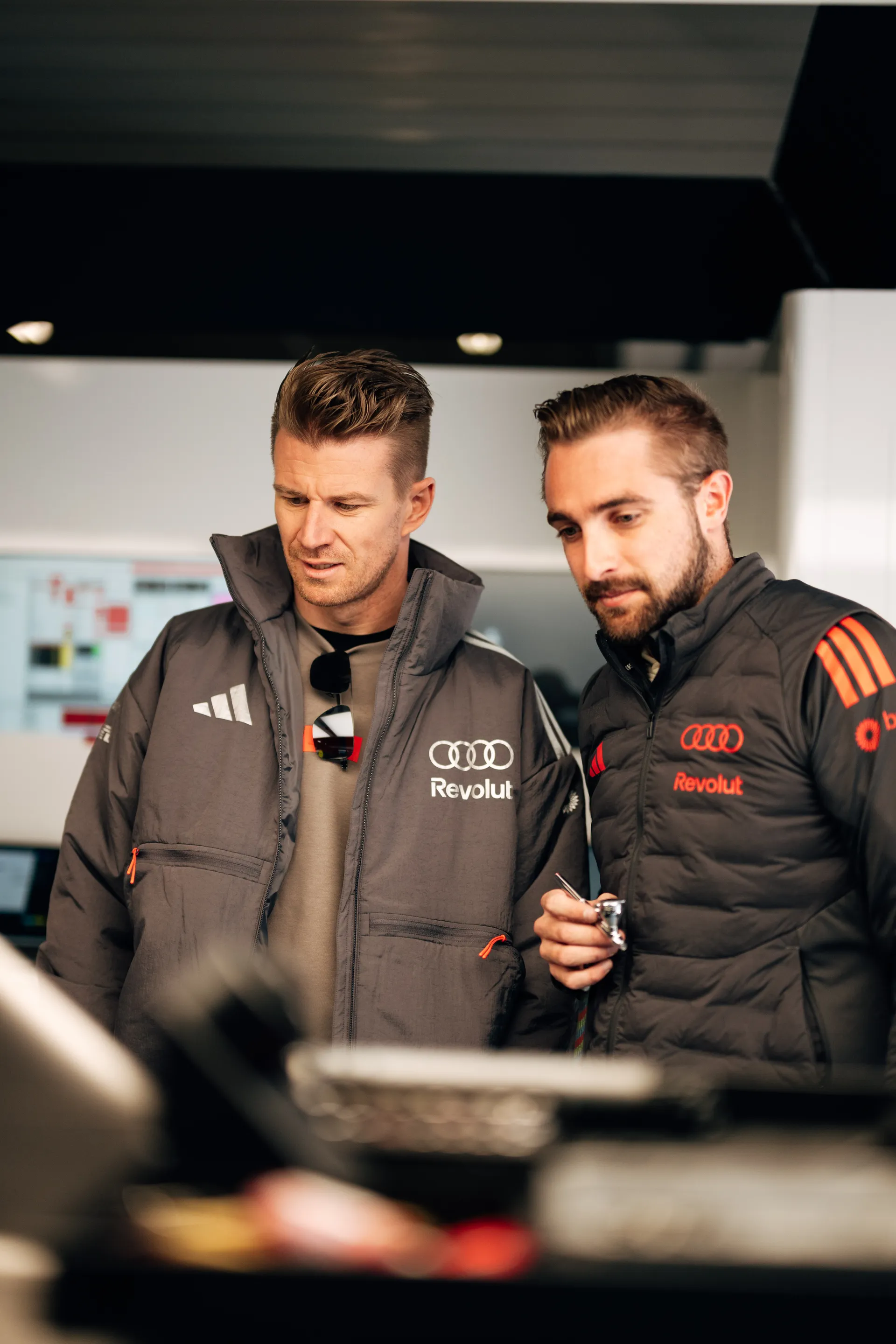 An Audi Revolut F1® Team driver Nico Hulkenberg and engineer review details together inside the team garage in Shanghai.