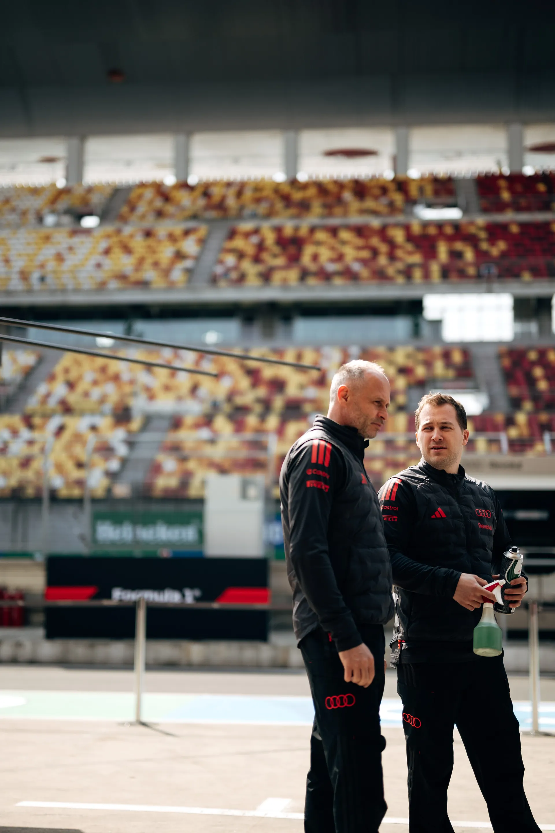 Audi Revolut F1® Team engineers stand trackside in Shanghai with the grandstands visible in the background.