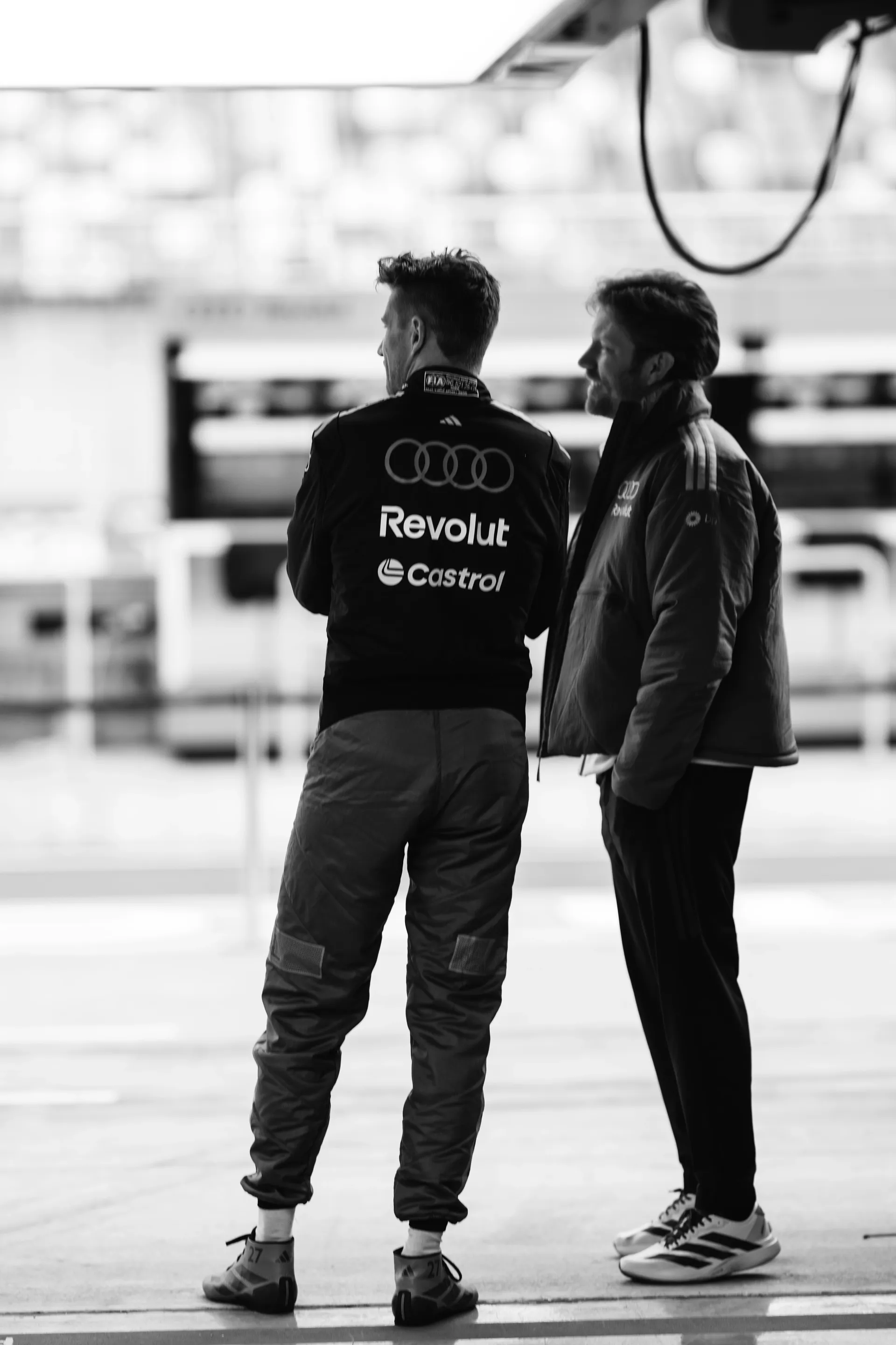 Rear view of team members speaking with a team member inside the Audi Revolut F1® Team garage in Shanghai.