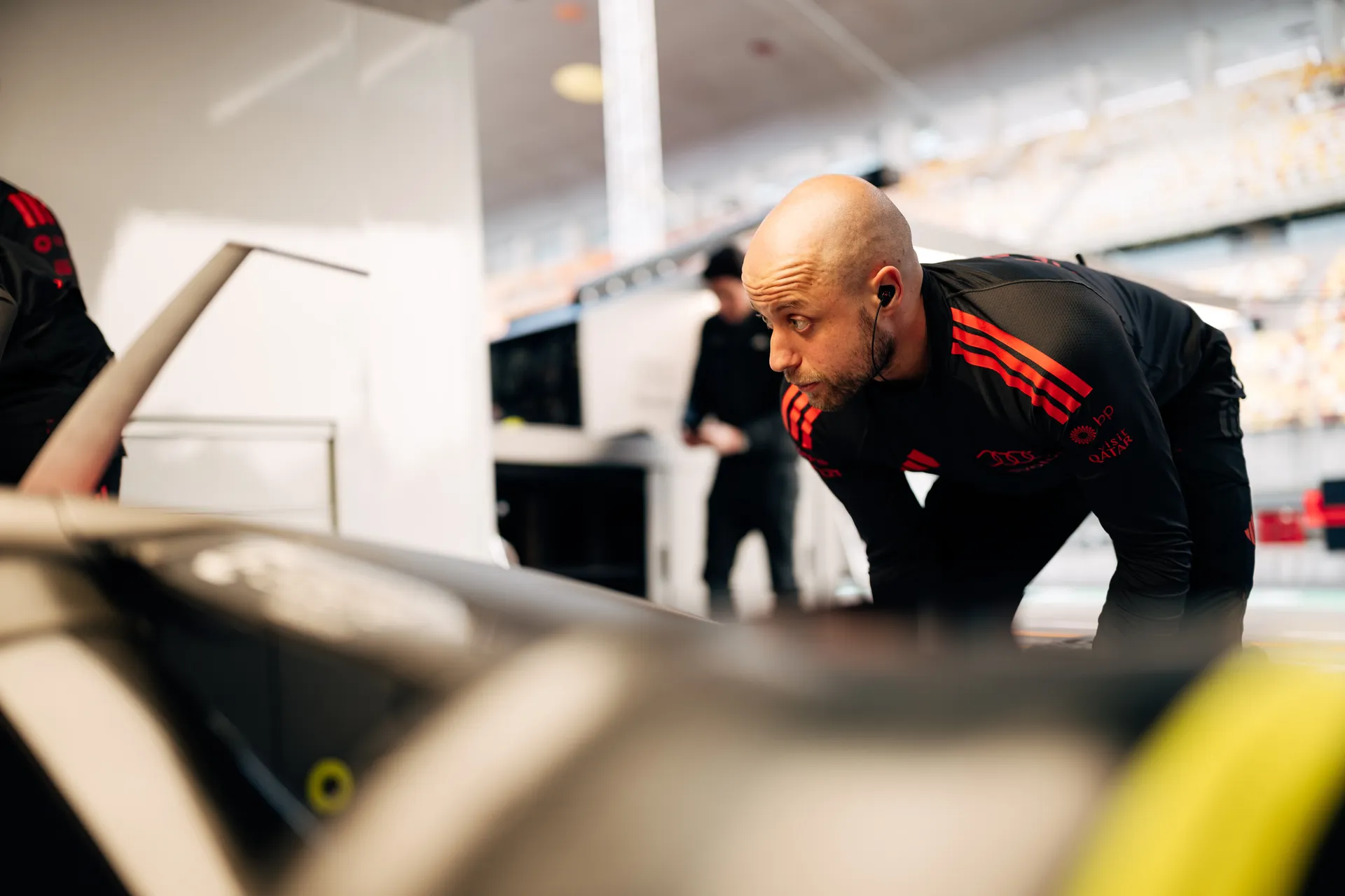 Audi Revolut F1® Team crew member leans over race car components inside the Shanghai garage during setup work.