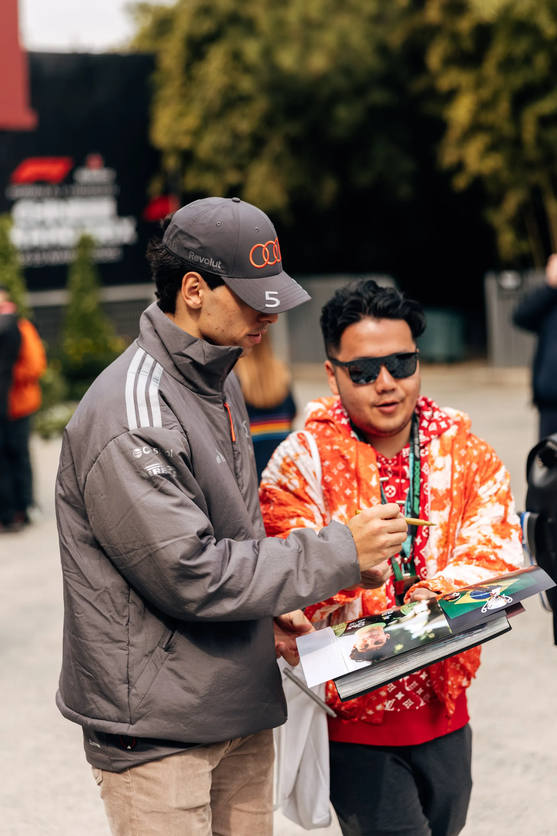 Gabriel Bortoleto signs autographs for a fan in the paddock during race day arrival at the Chinese Grand Prix.