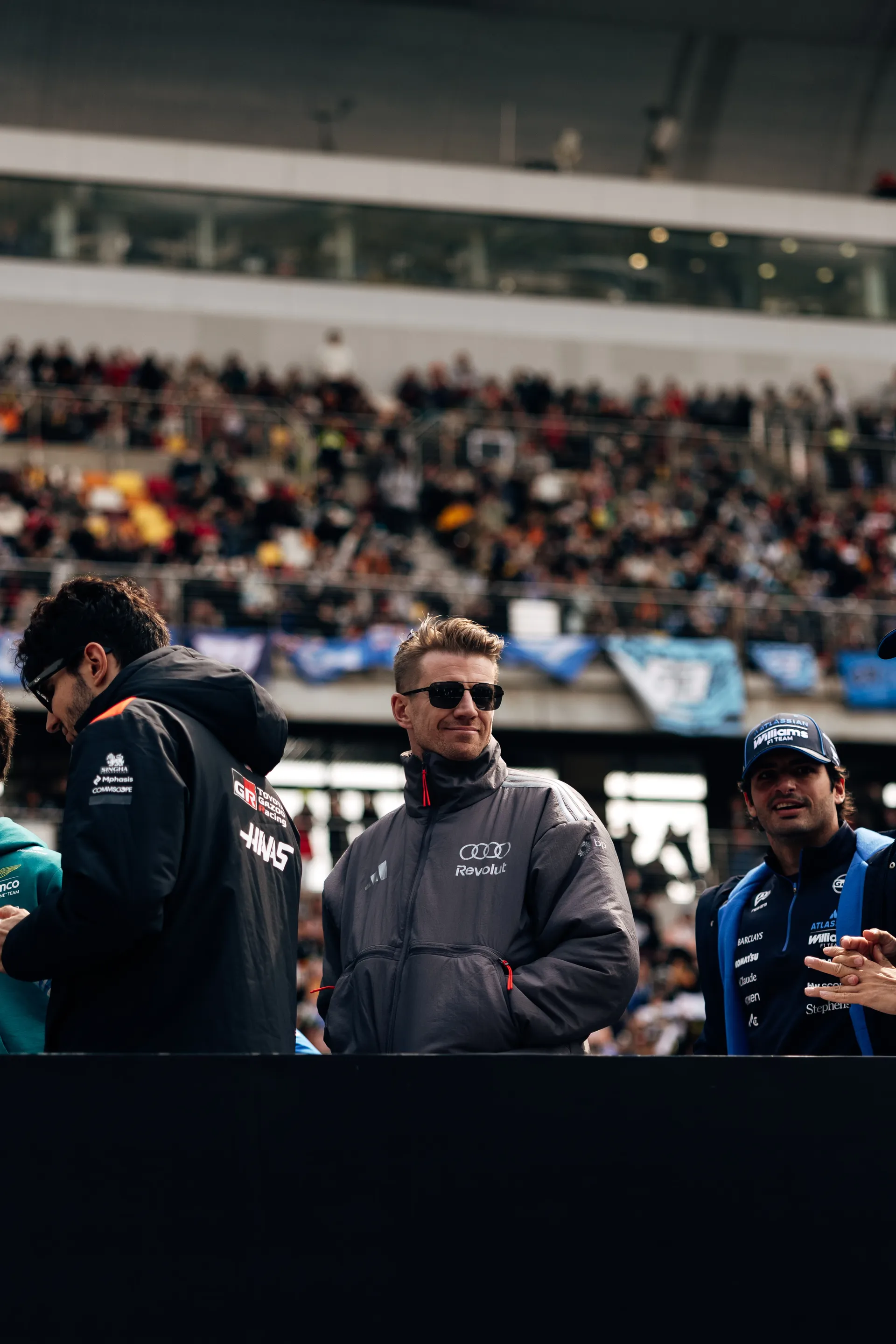 Nico Hulkenberg stands among other drivers during a paddock appearance in front of the crowd at the Chinese Grand Prix, with the Audi Revolut F1® Team branding visible on his jacket.