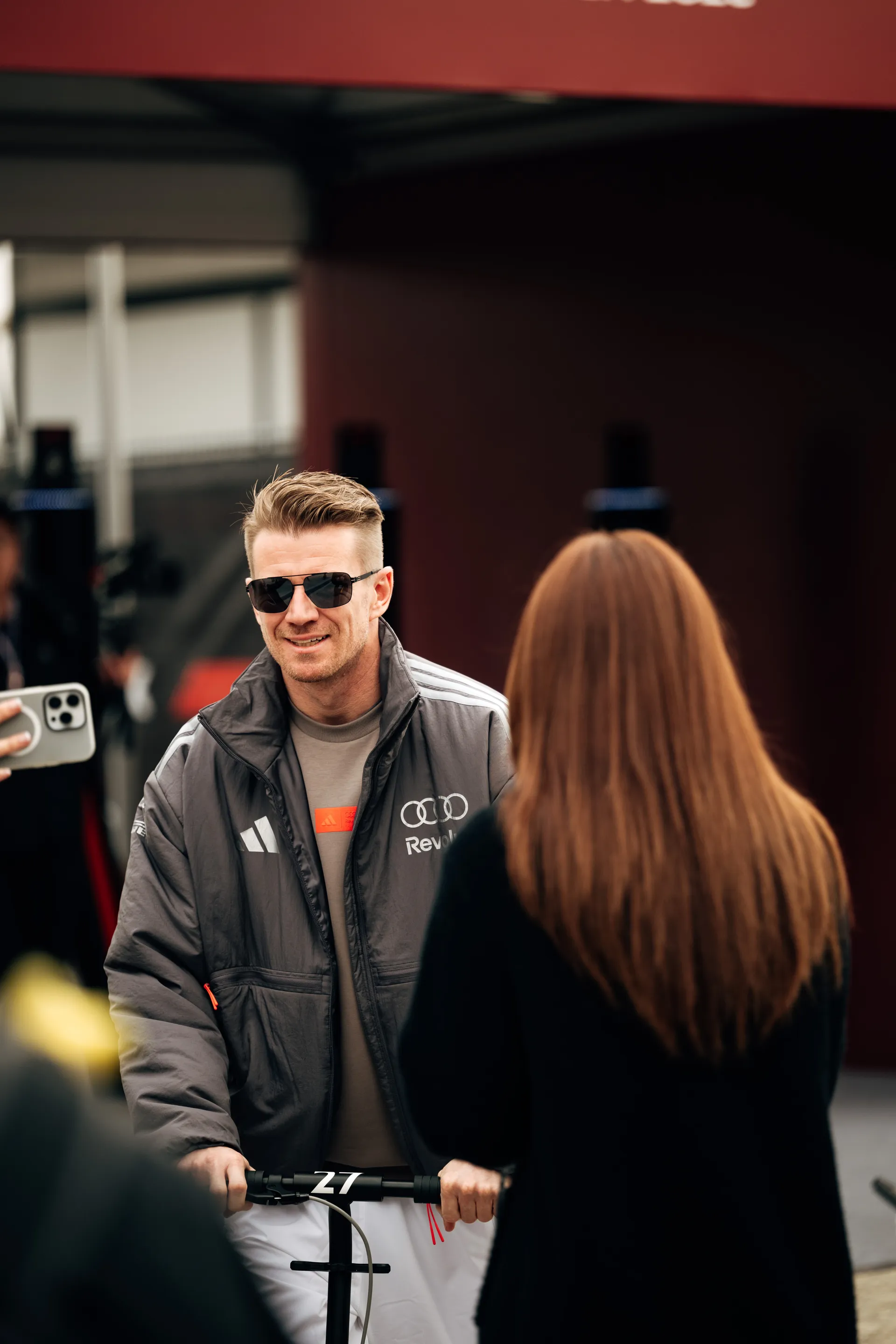 Nico Hulkenberg arrives on a scooter in Audi Revolut F1® Team outerwear during race day at the Chinese Grand Prix.
