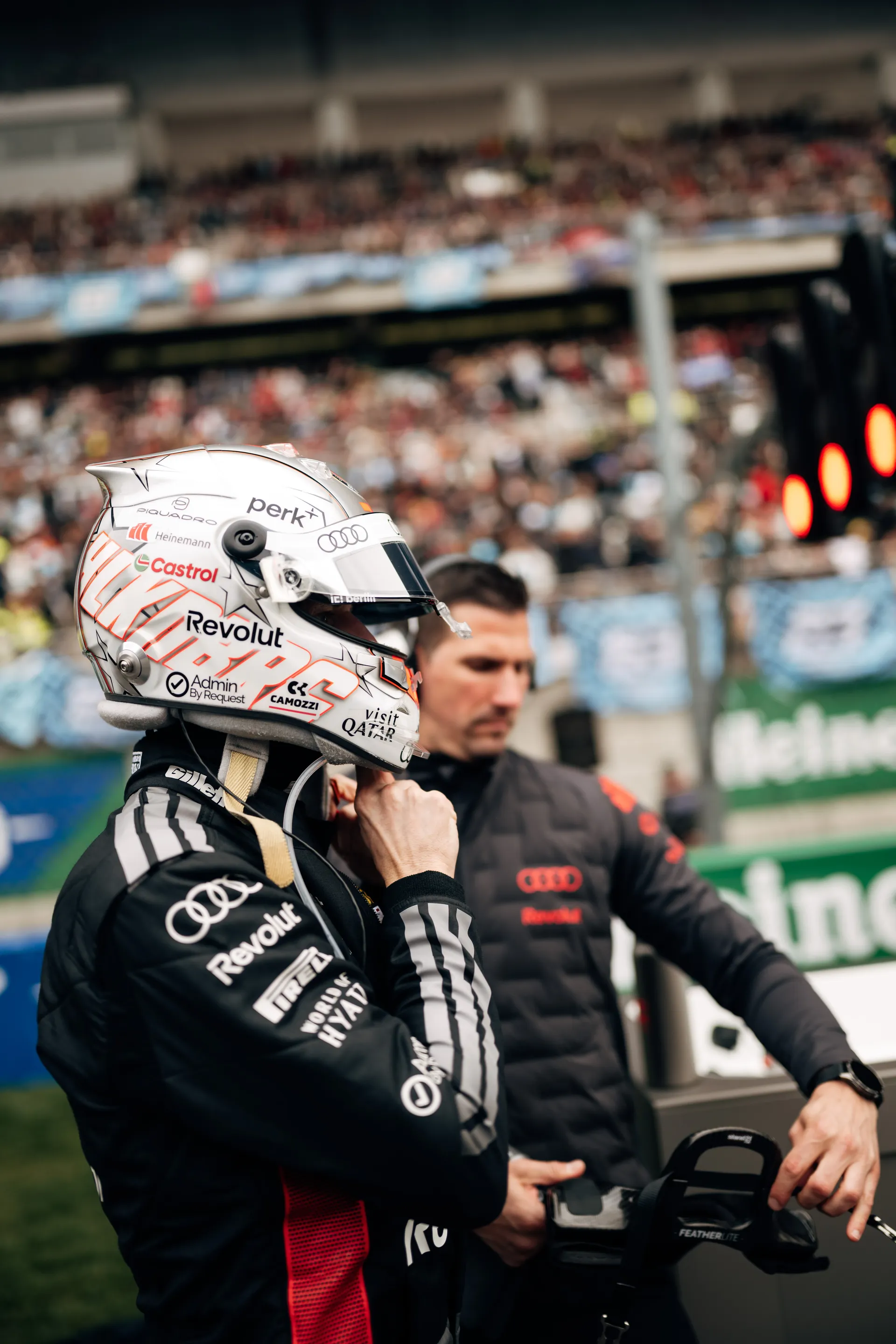 Nico Hulkenberg fastens his helmet strap beside the Audi Revolut F1® Team car on the grid at the Chinese Grand Prix.