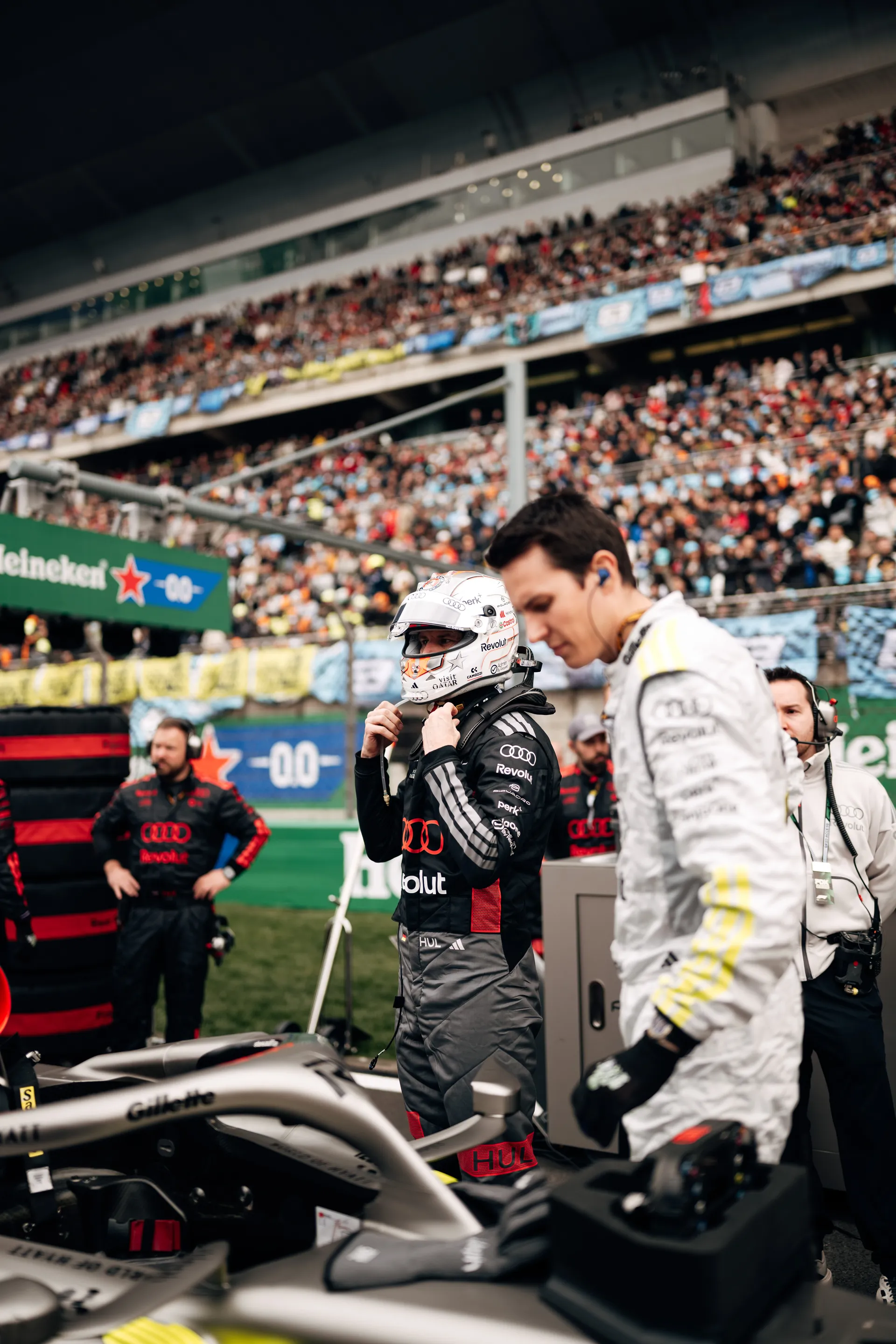 Nico Hulkenberg stands beside the Audi Revolut F1® Team car on the grid with team members during pre-race preparations in Shanghai.