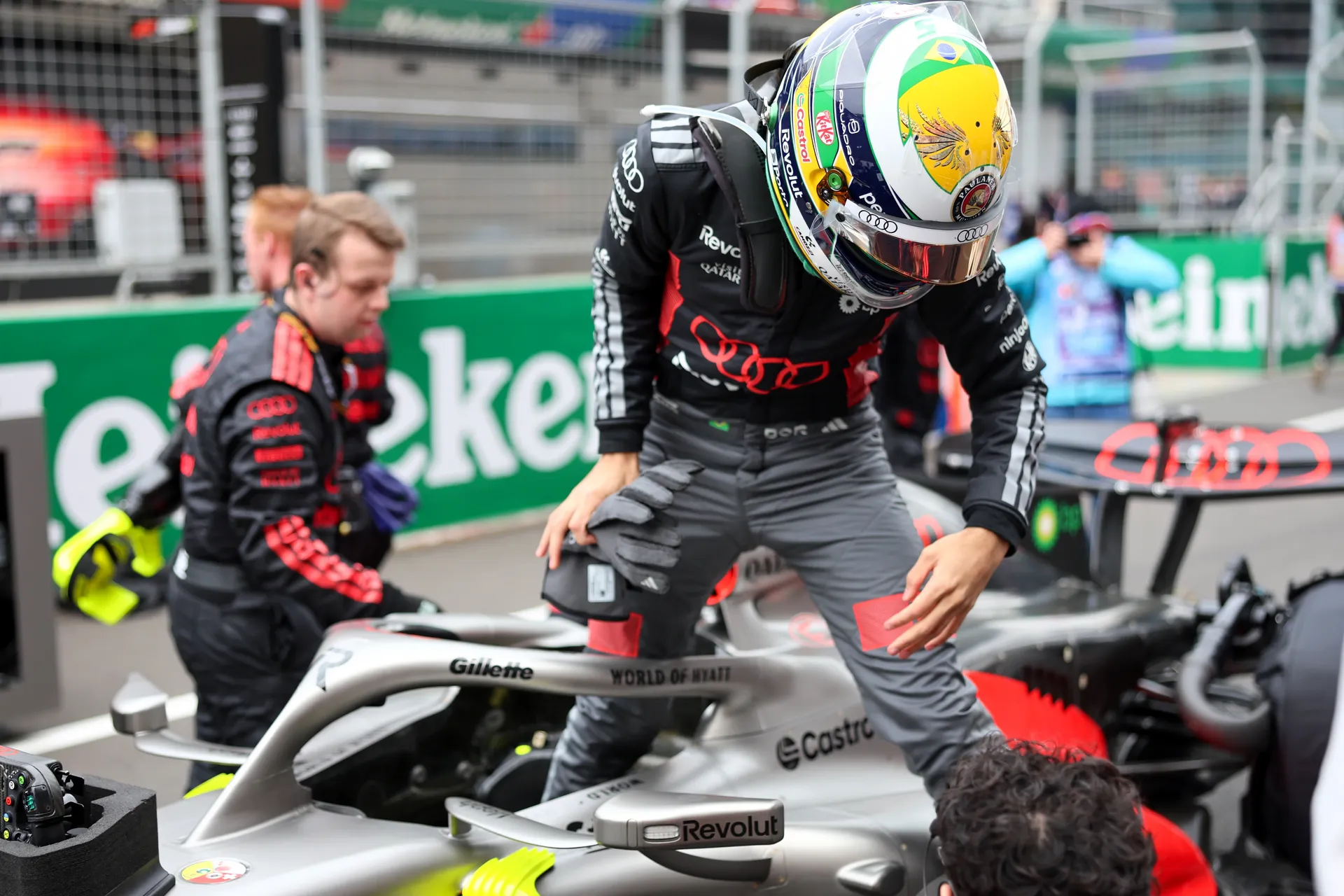 Gabriel Bortoleto climbs out of the Audi Revolut F1® Team car on the grid before the Chinese Grand Prix, wearing his green and yellow helmet.