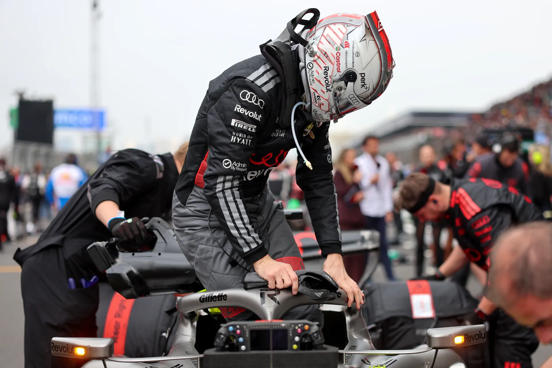 Nico Hulkenberg climbs into the Audi Revolut F1® Team car on the grid before the Chinese Grand Prix, surrounded by team members during final preparations.