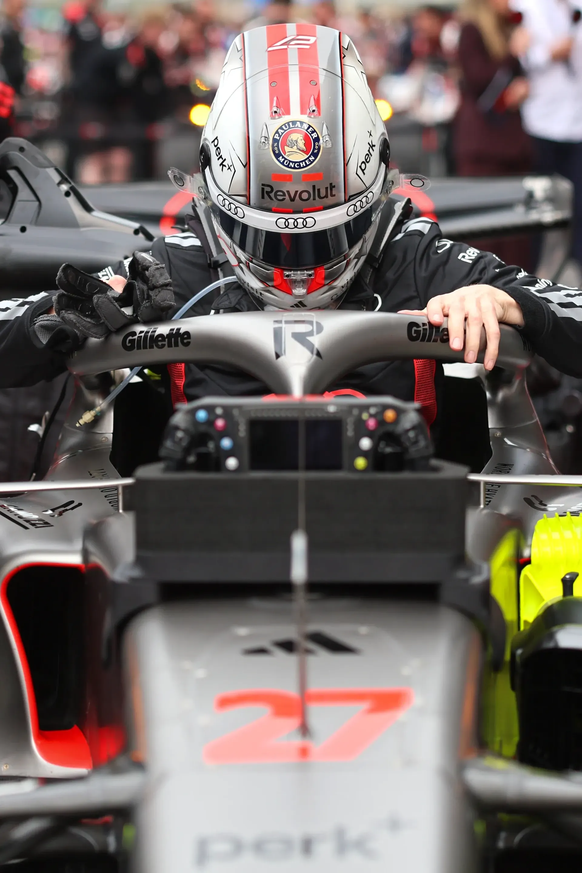 Front view of Nico Hulkenberg seated in the Audi Revolut F1® Team car on the grid before the Chinese Grand Prix, wearing his helmet behind the halo.