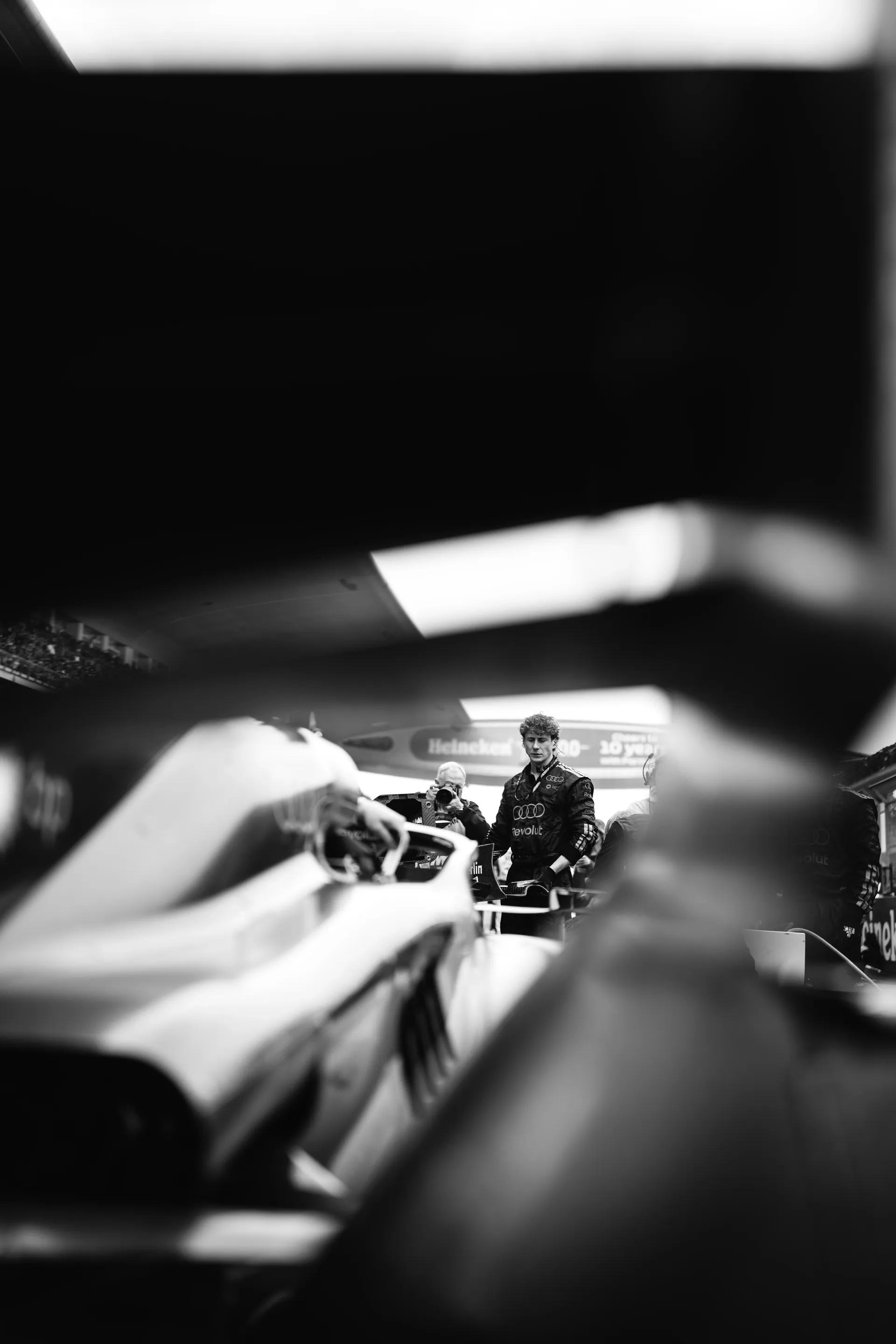 Black and white image of team member seen through the Audi Revolut F1® Team car on the grid before the Chinese Grand Prix.