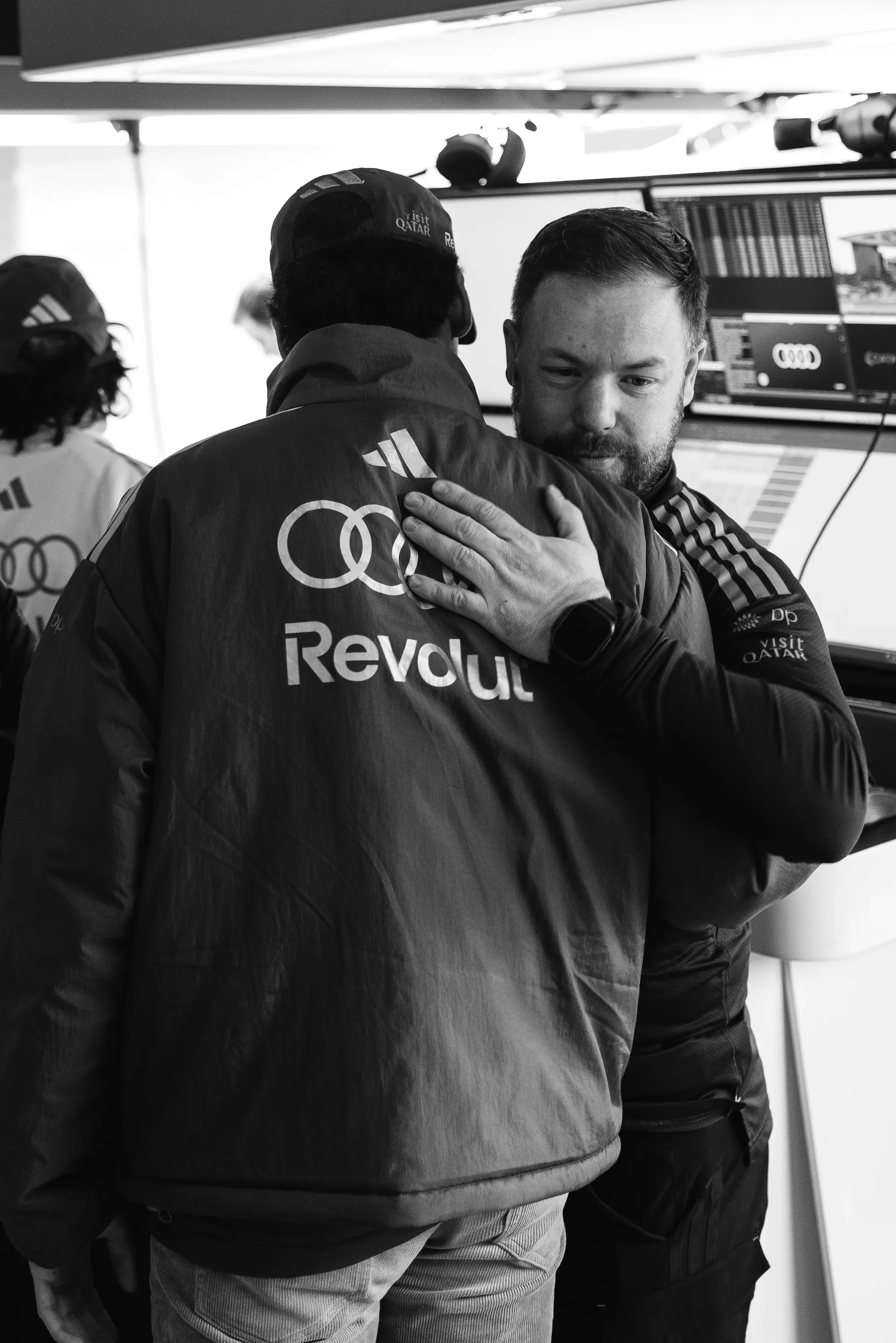 Gabriel Bortoleto hugs an Audi Revolut F1® Team colleague inside the garage in a black and white image during the Chinese Grand Prix weekend.
