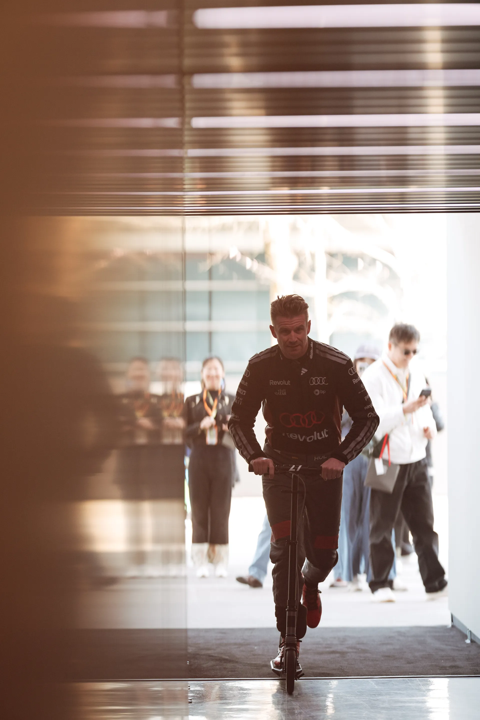 Nico Hulkenberg rides a scooter through the Audi Revolut F1® Team garage entrance area during the Chinese Grand Prix weekend.