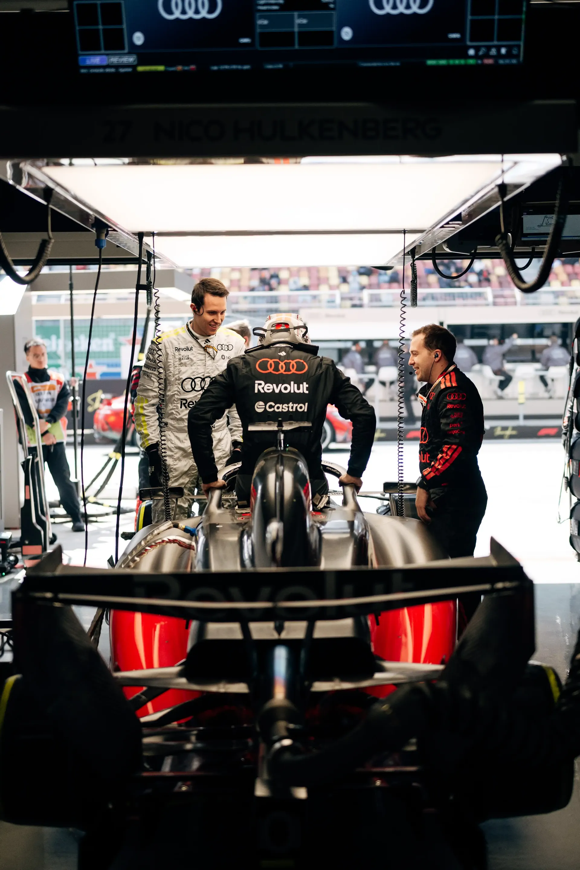 Audi Revolut F1® Team car surrounded by crew members and activity in the Formula 1 paddock.